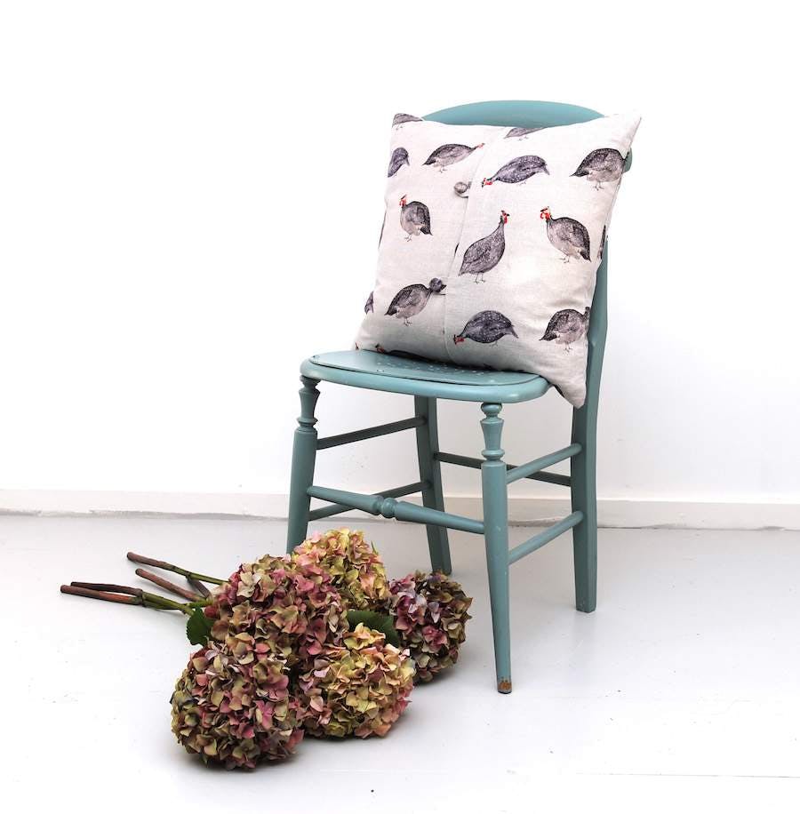Cushion with a print of birds placed on a light green chair