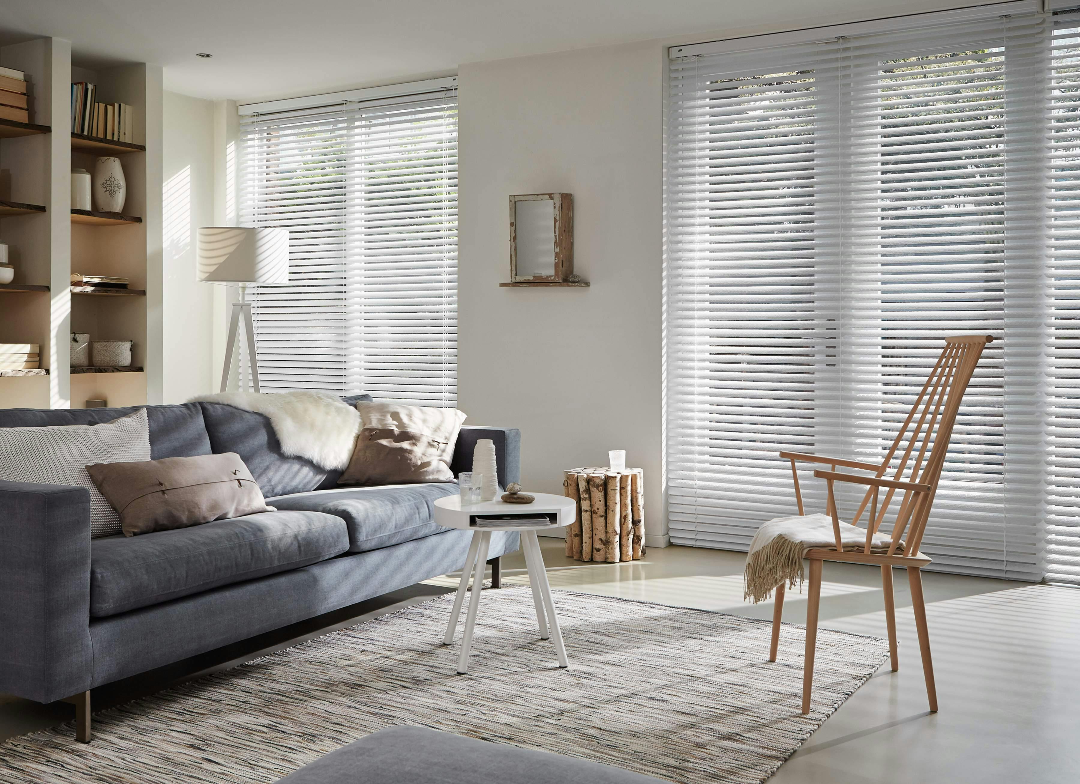 Sunny living room with white Venetian blinds on large windows and patio door