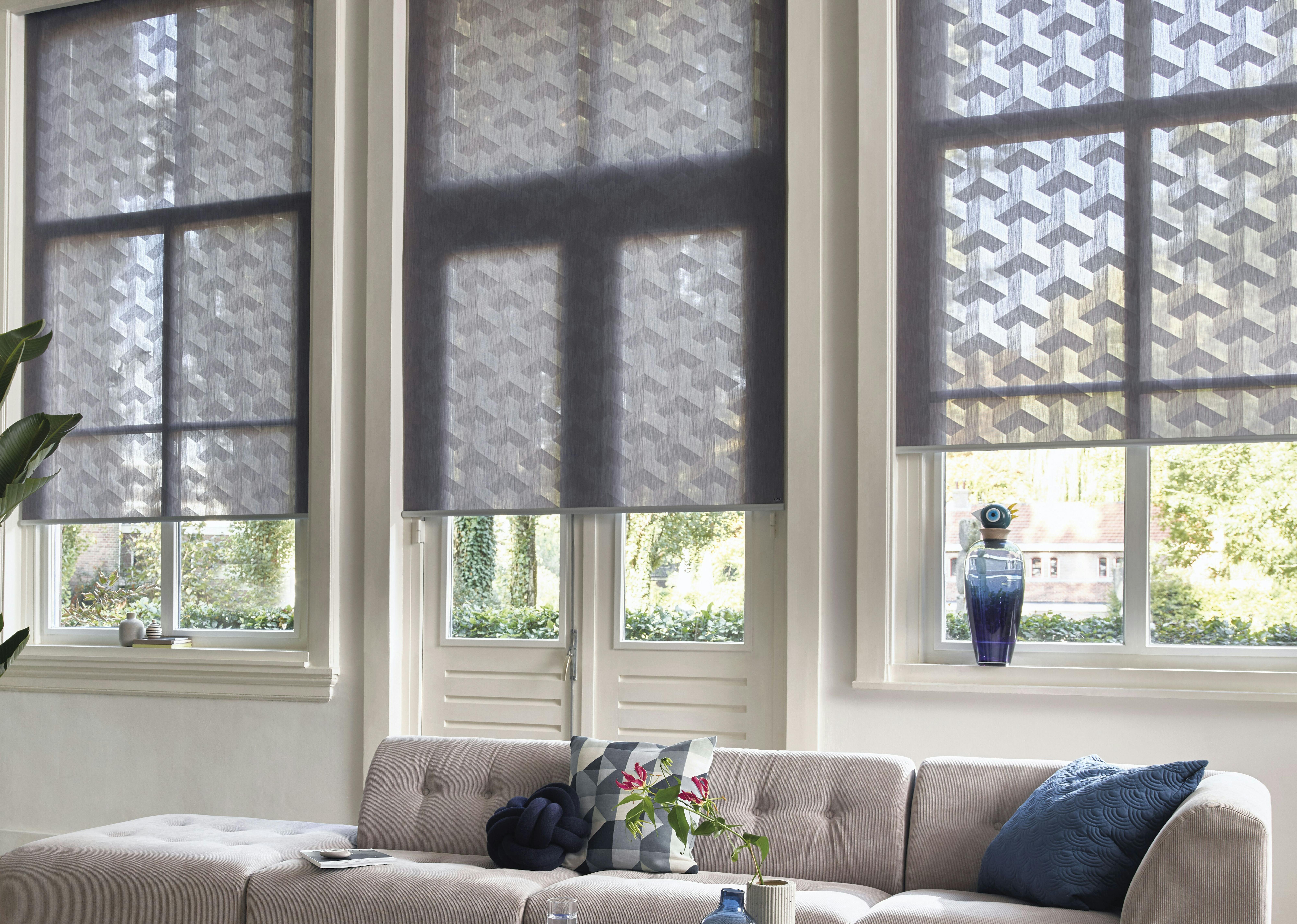 Modern living room with grey patterned roller blinds on windows and patio door