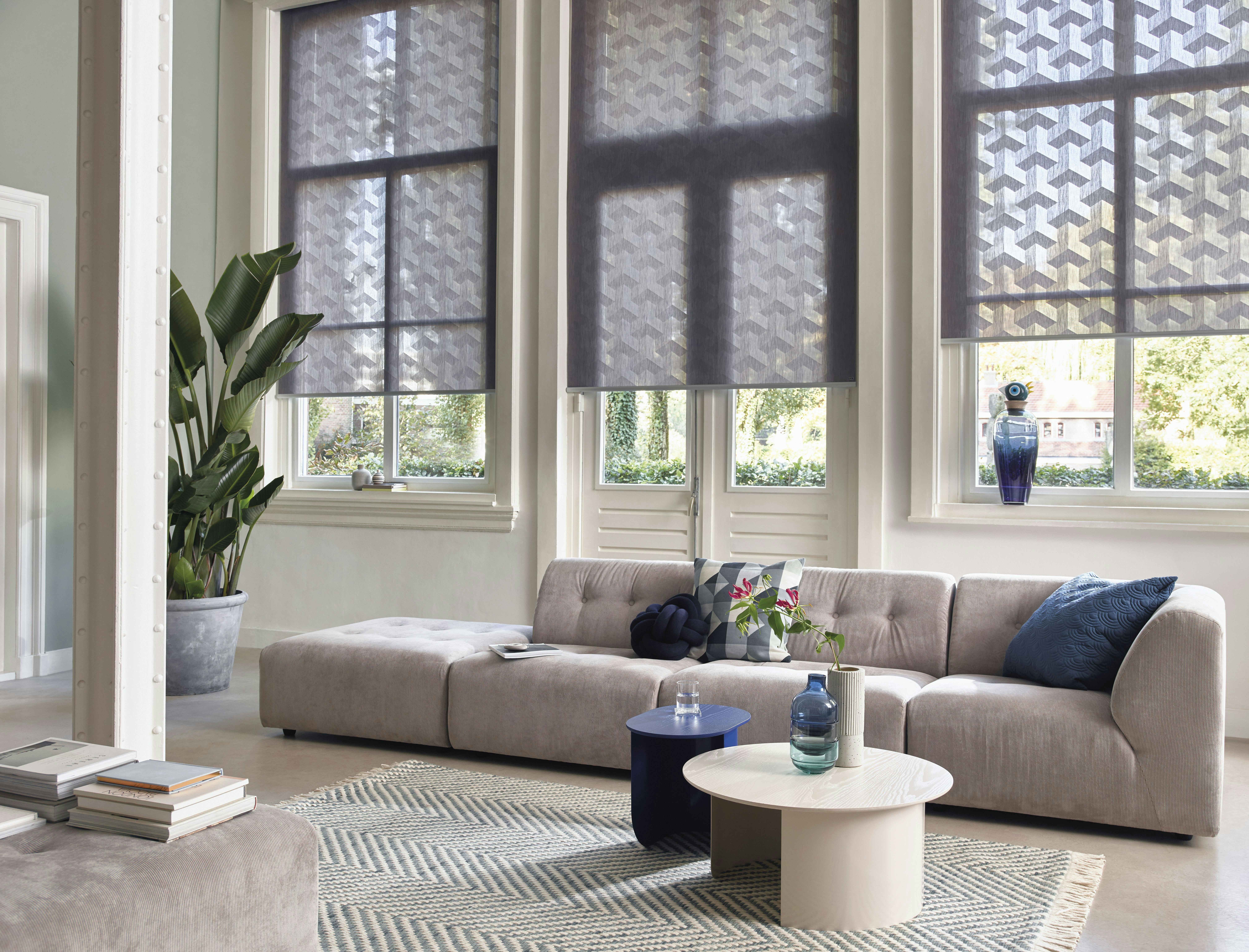 Modern living room with grey patterned roller blinds on windows and patio door