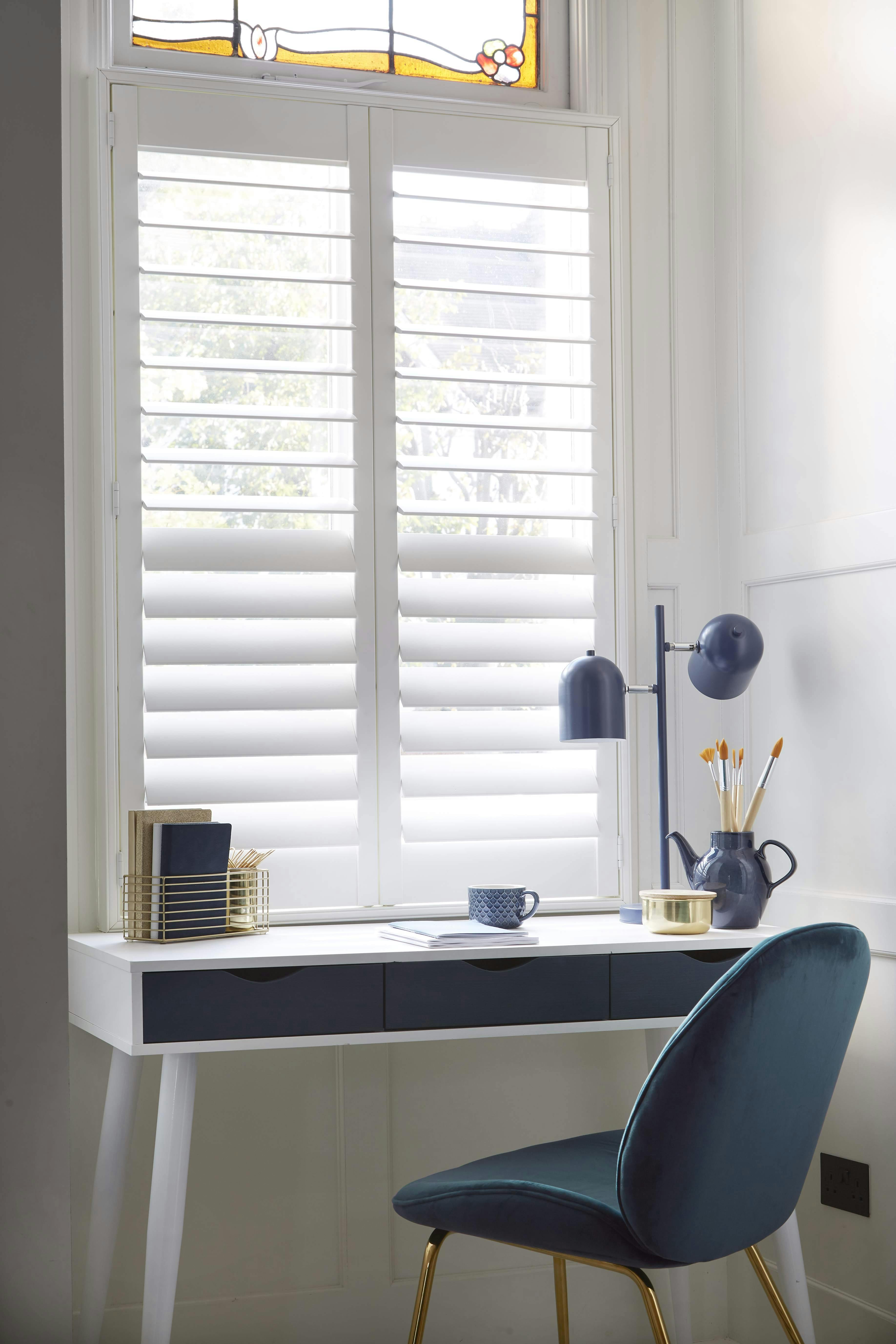 White Shutters on a window next to a small desk