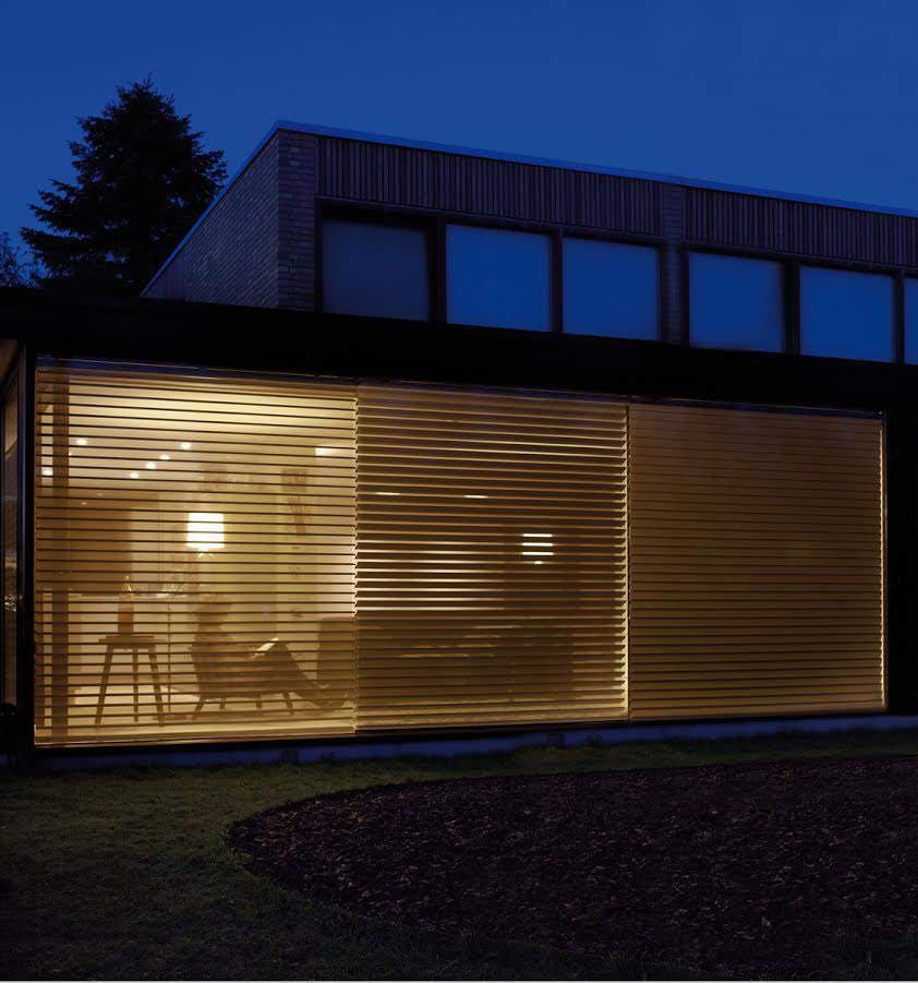 Side view of a house with cream Outside blinds on large windows