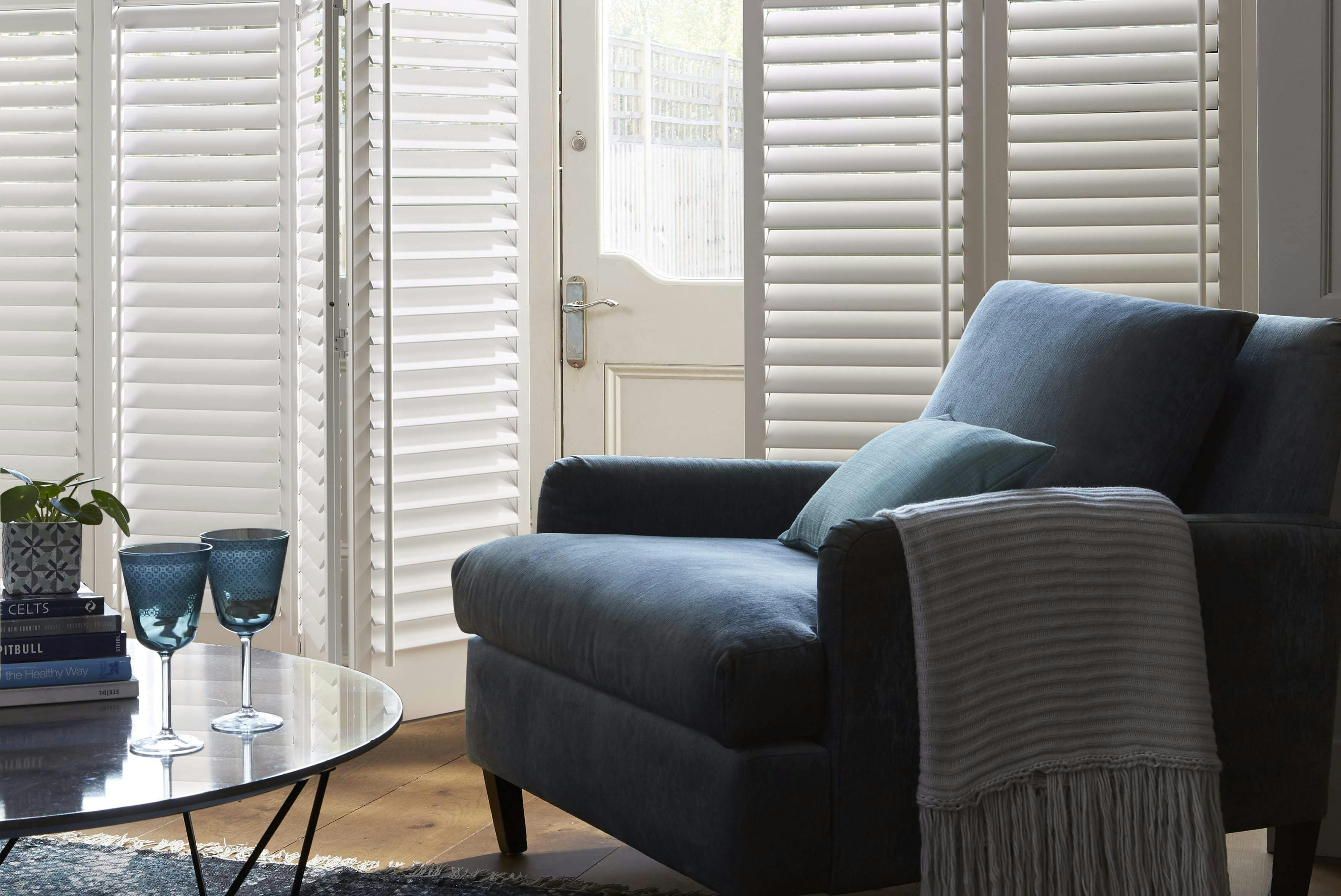 Living room with blue armchair and white Shutters on windows