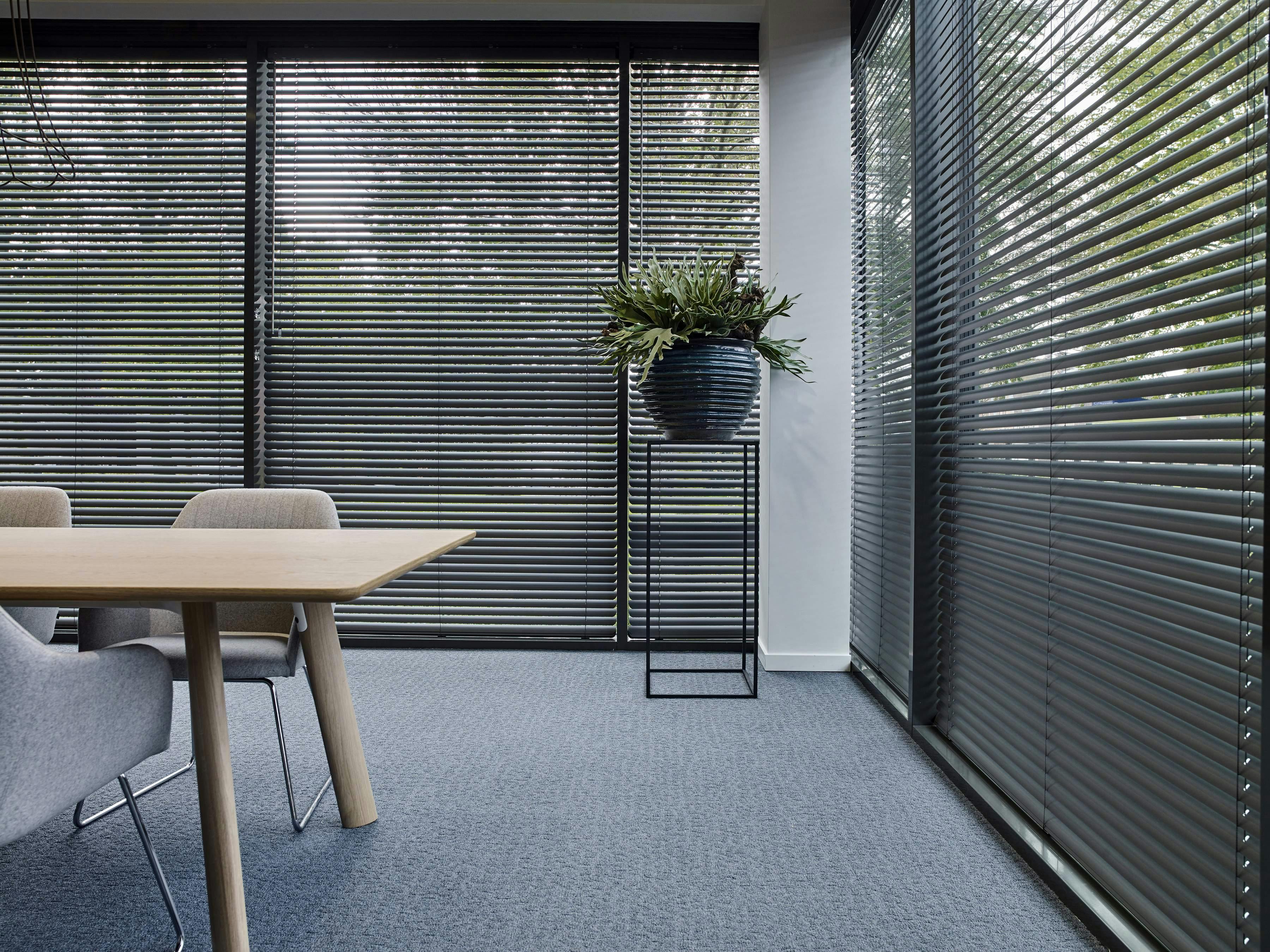 Spacious room with black Venetian blinds on large windows