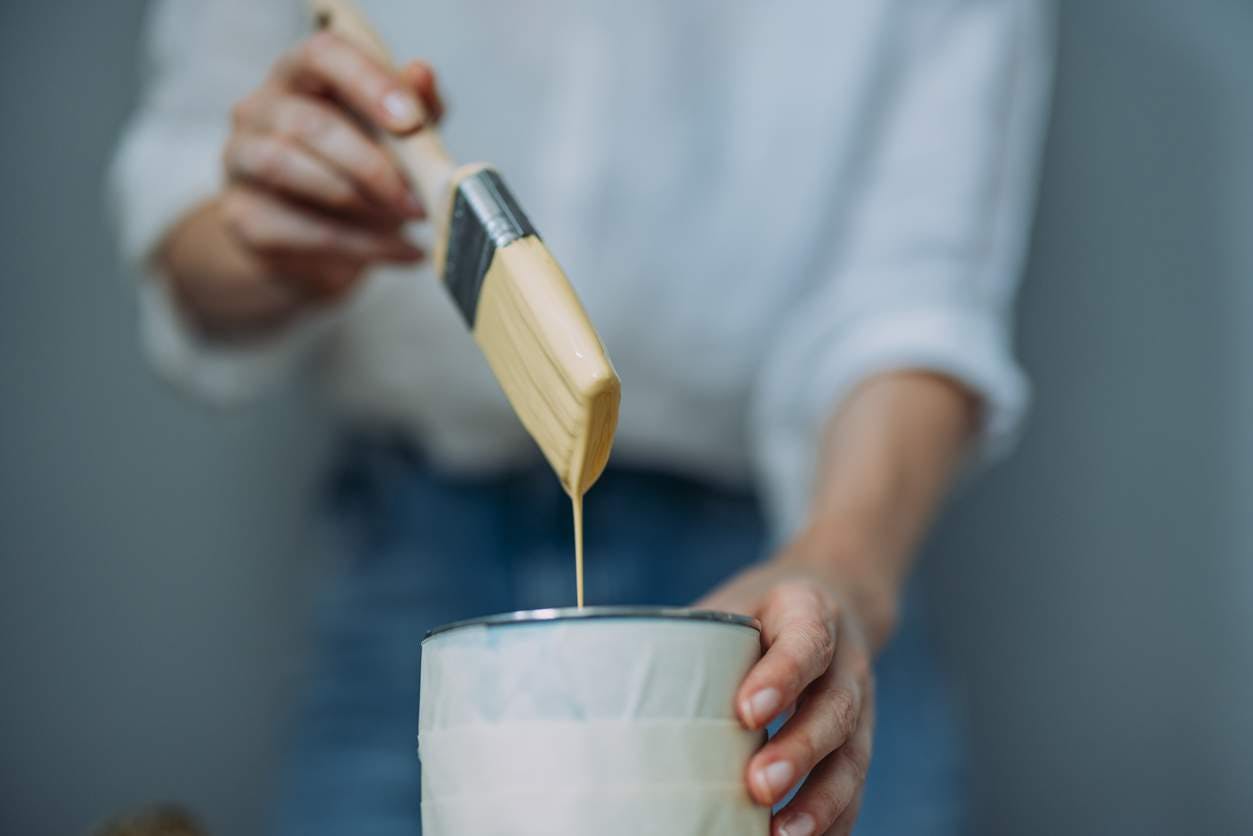 Close up of a woman with a paint brush and a paint can 