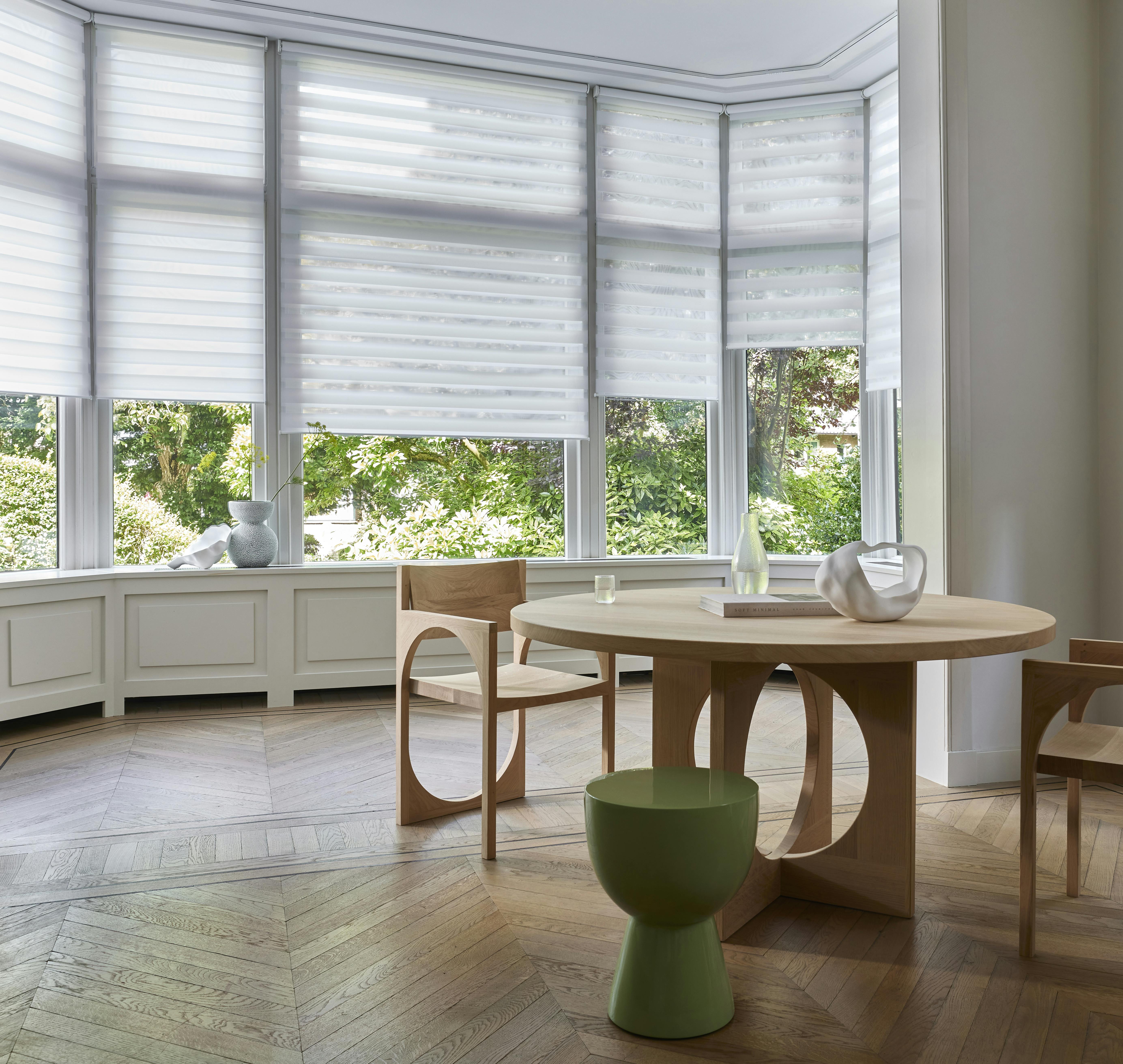 A bright living room with white duo roller blinds on large windows