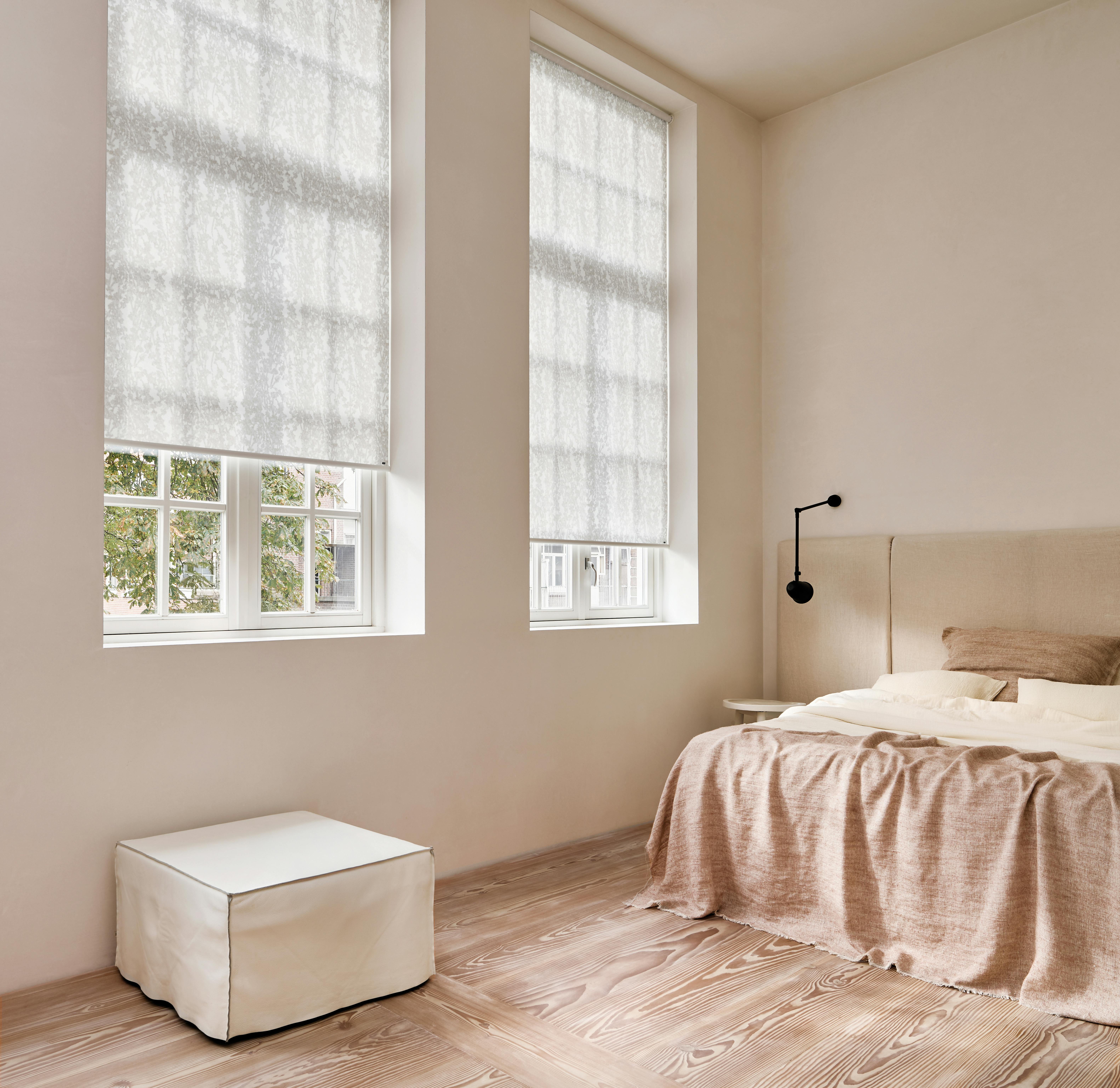 Light spacious bedroom with white roller blinds on windows