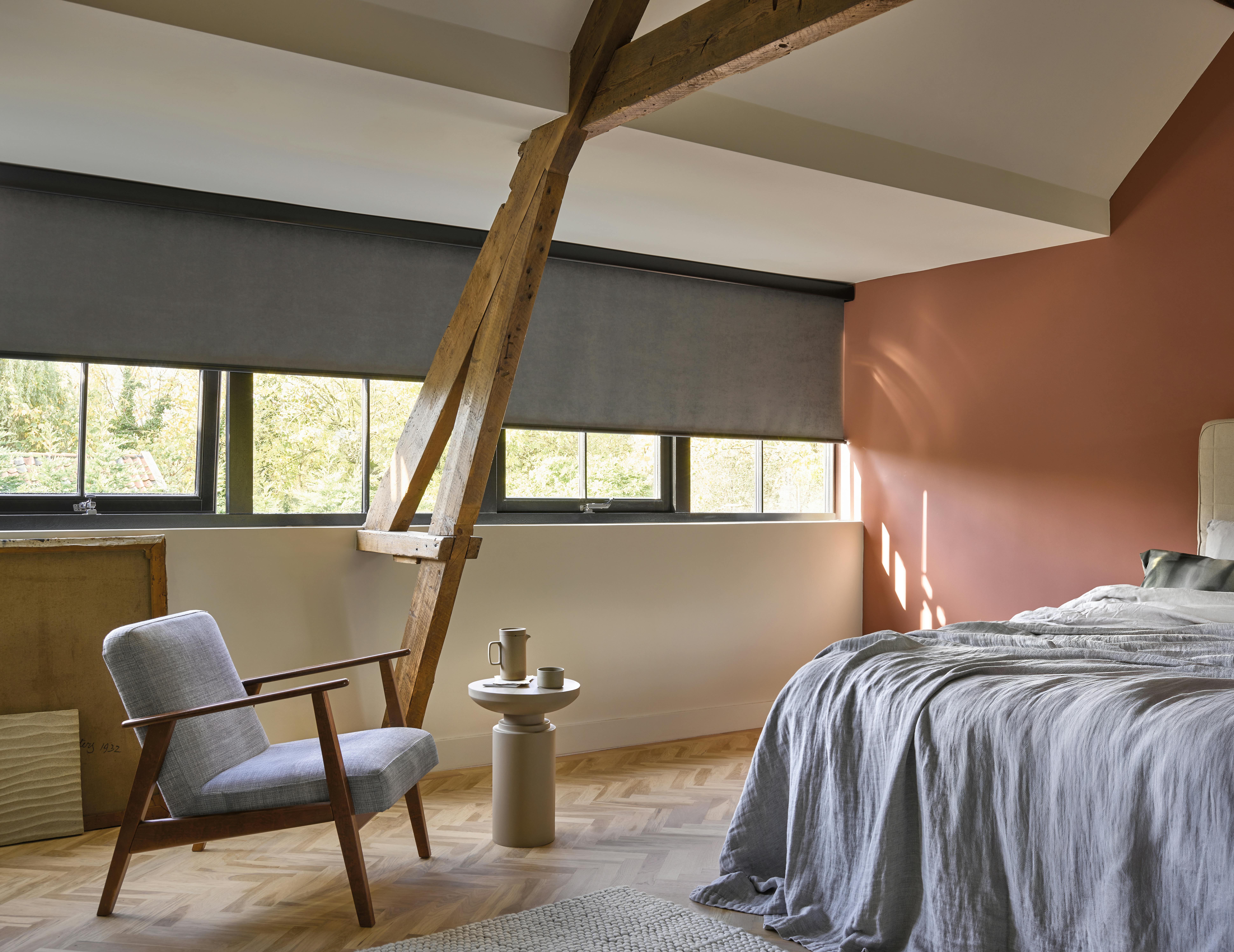 Spacious bedroom with grey roller blinds on windows