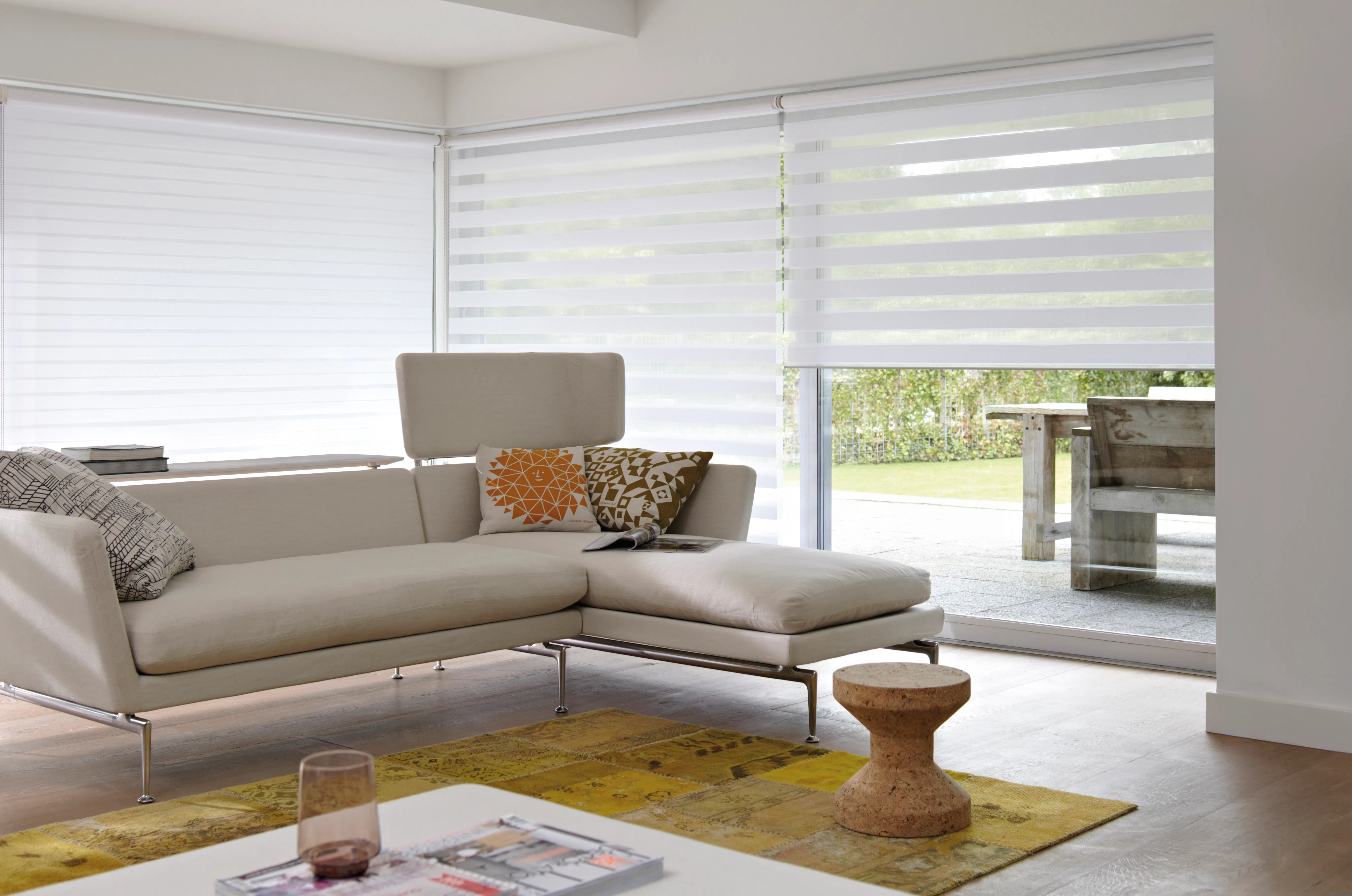 Light living room with white roller blinds on large windows