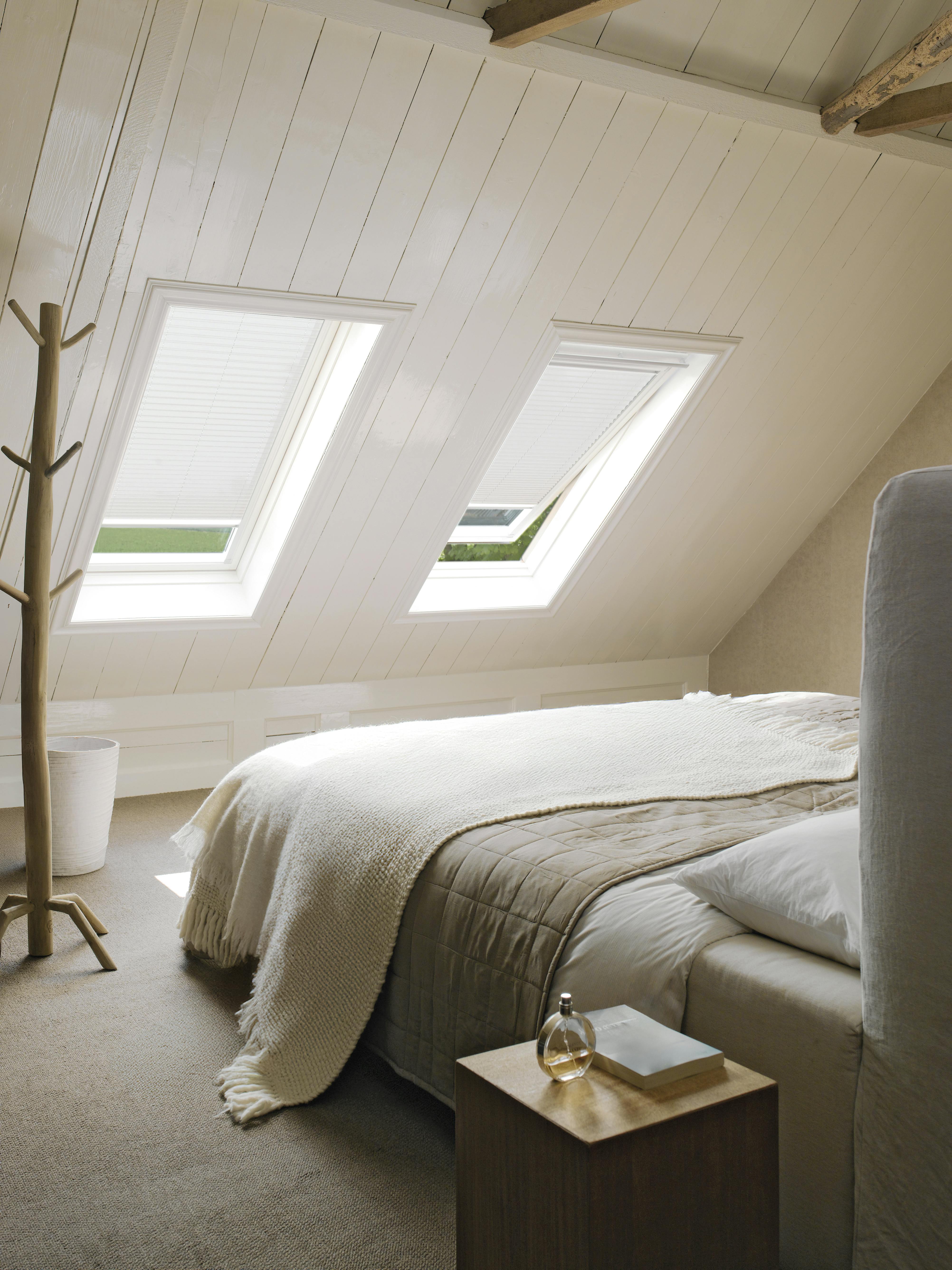 Witte plissé gordijnen op een dakraam in een slaapkamer