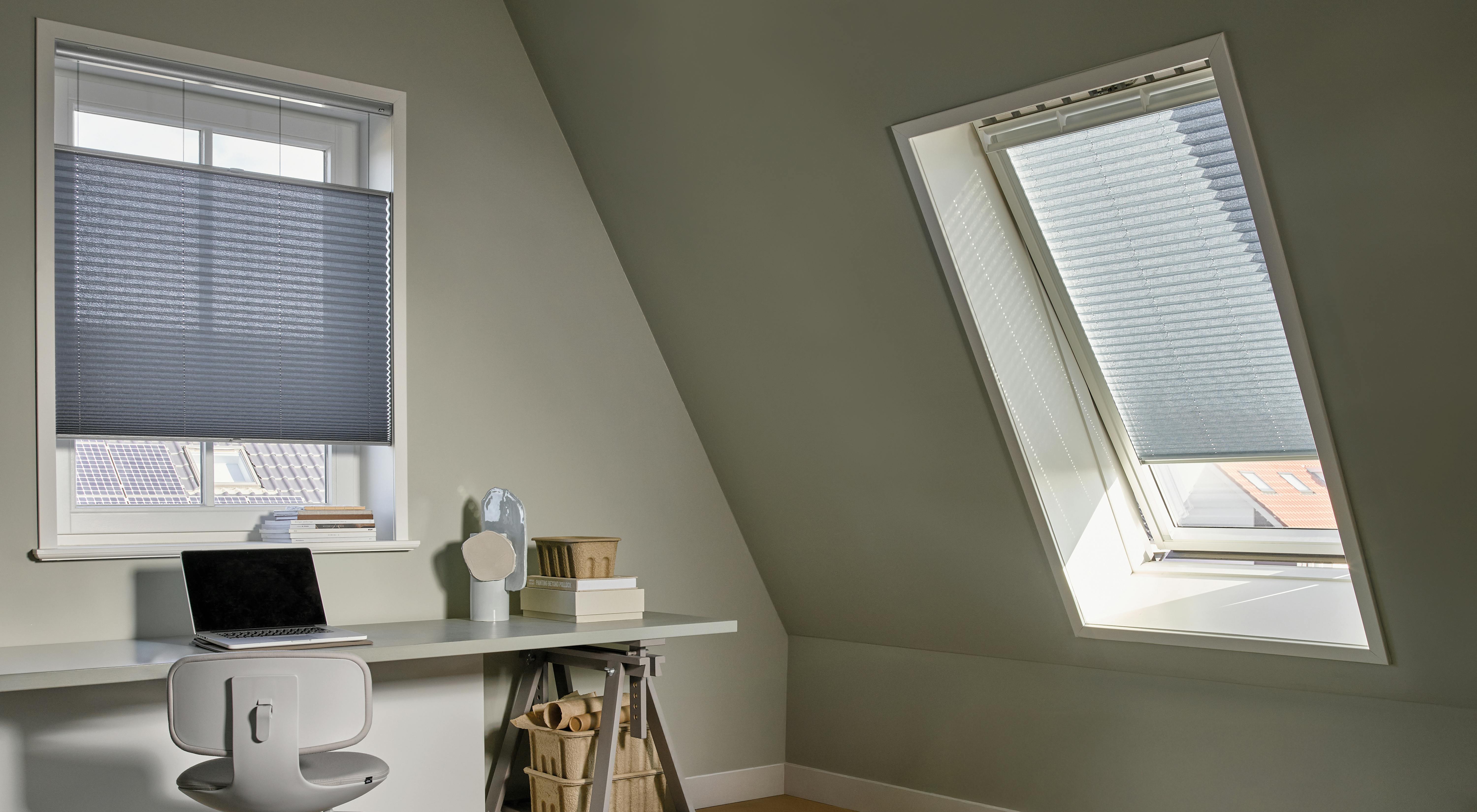 Blauwe plissé shades in een standaard- en dakraam in een loft van een thuiskantoor