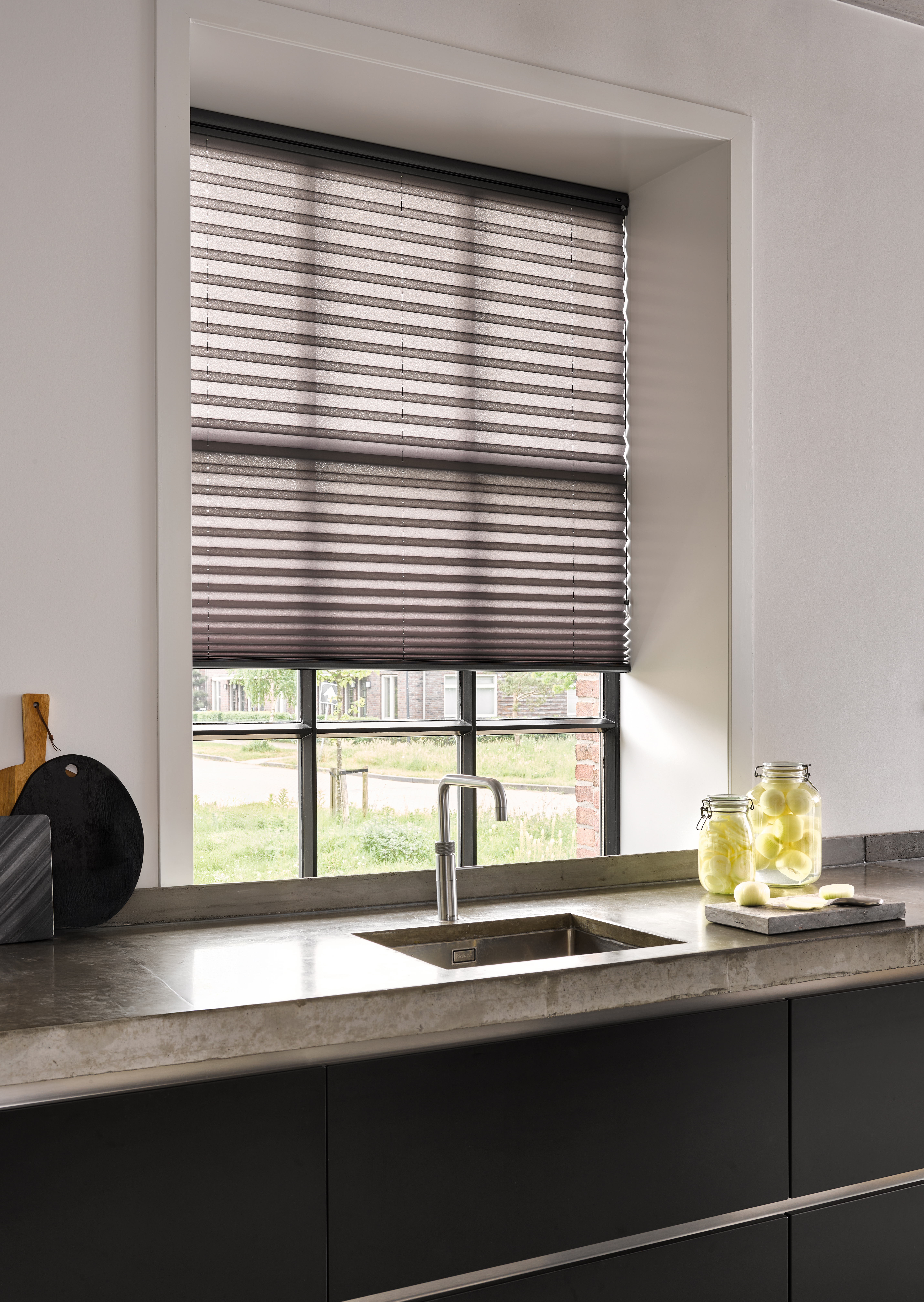 Zwarte plissé shades op een keukenraam