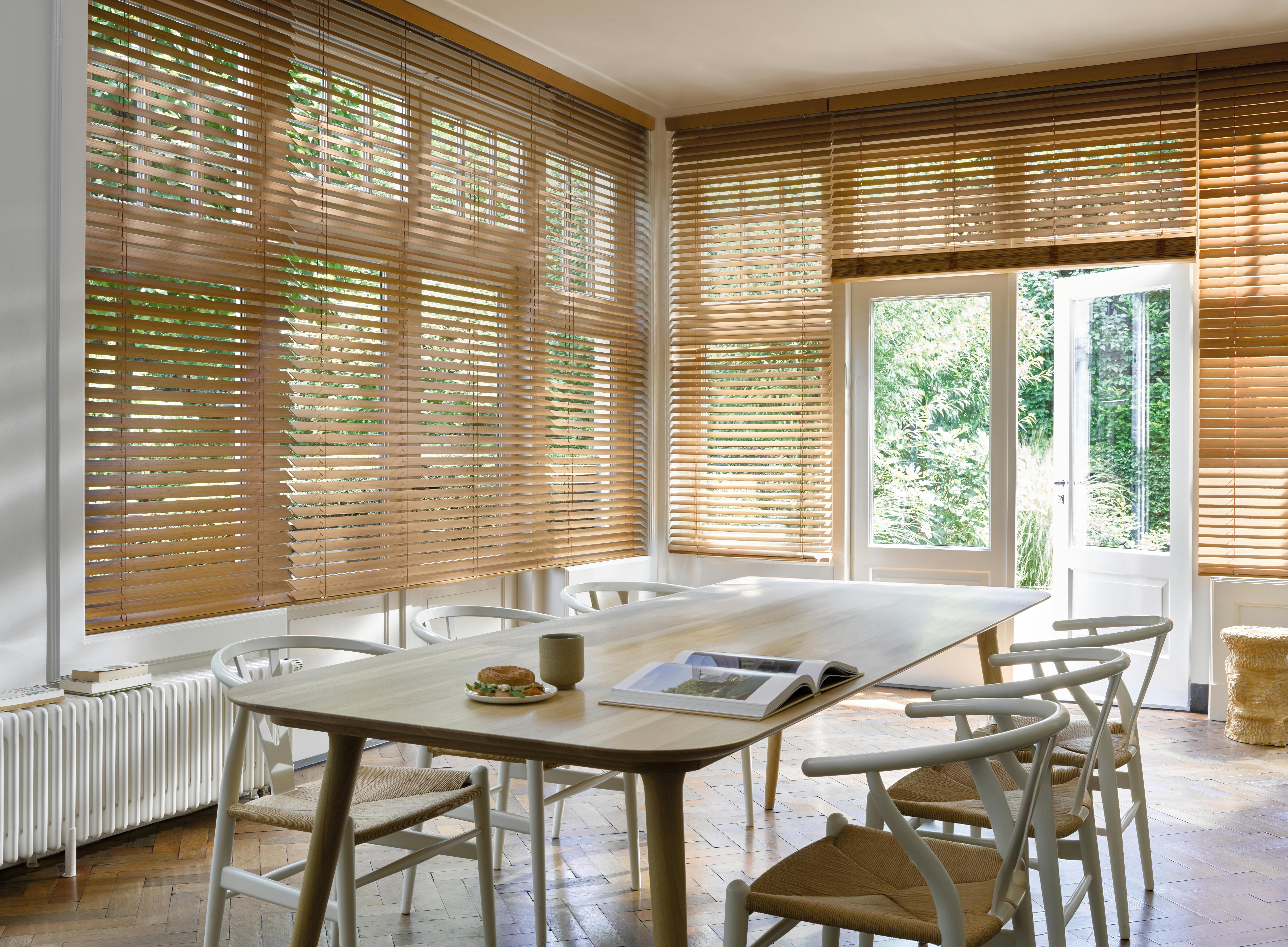 Bruine houten jaloezieën op ramen in een ruime eetkamer