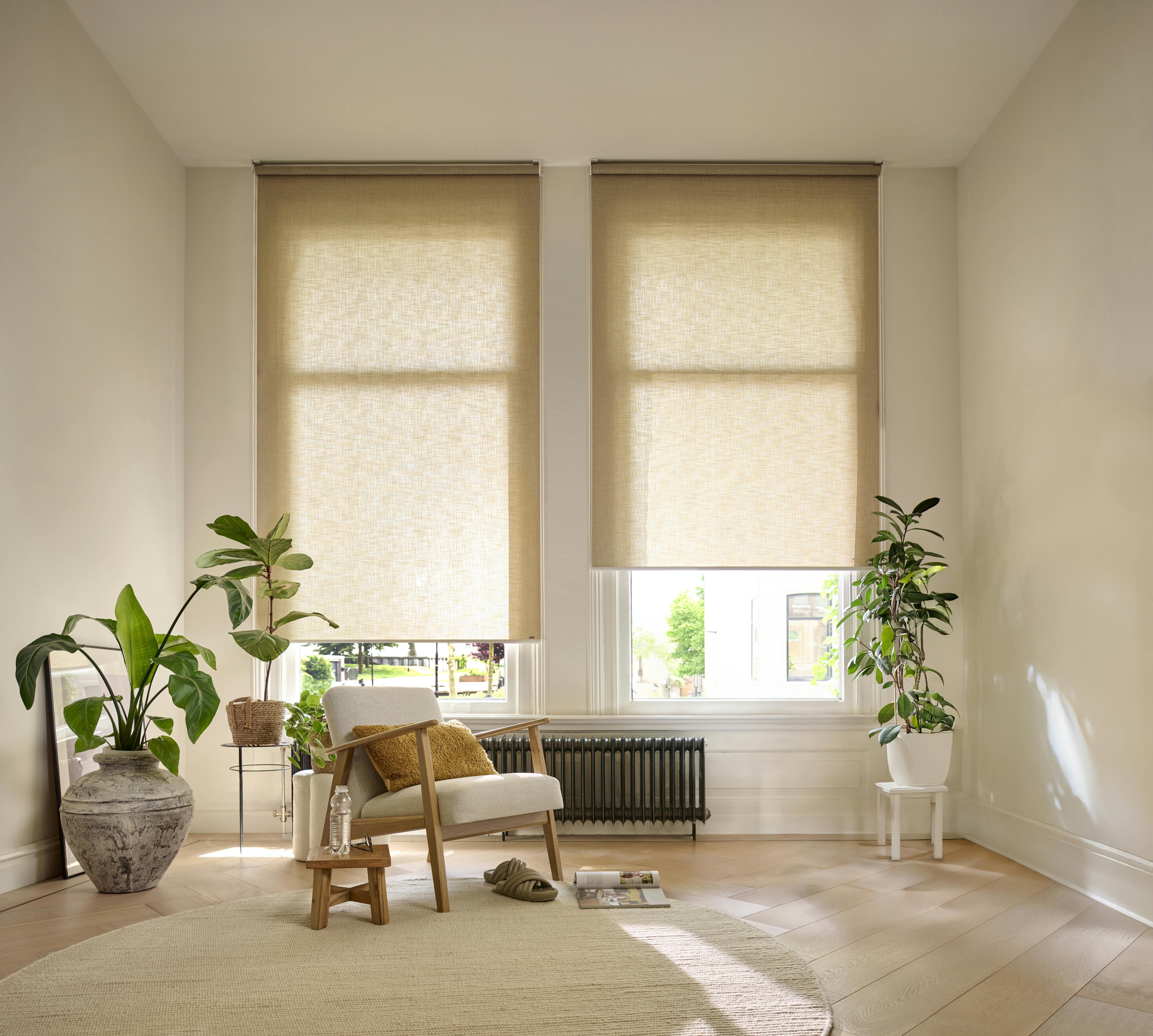 Spacious room with cream roller blinds on windows