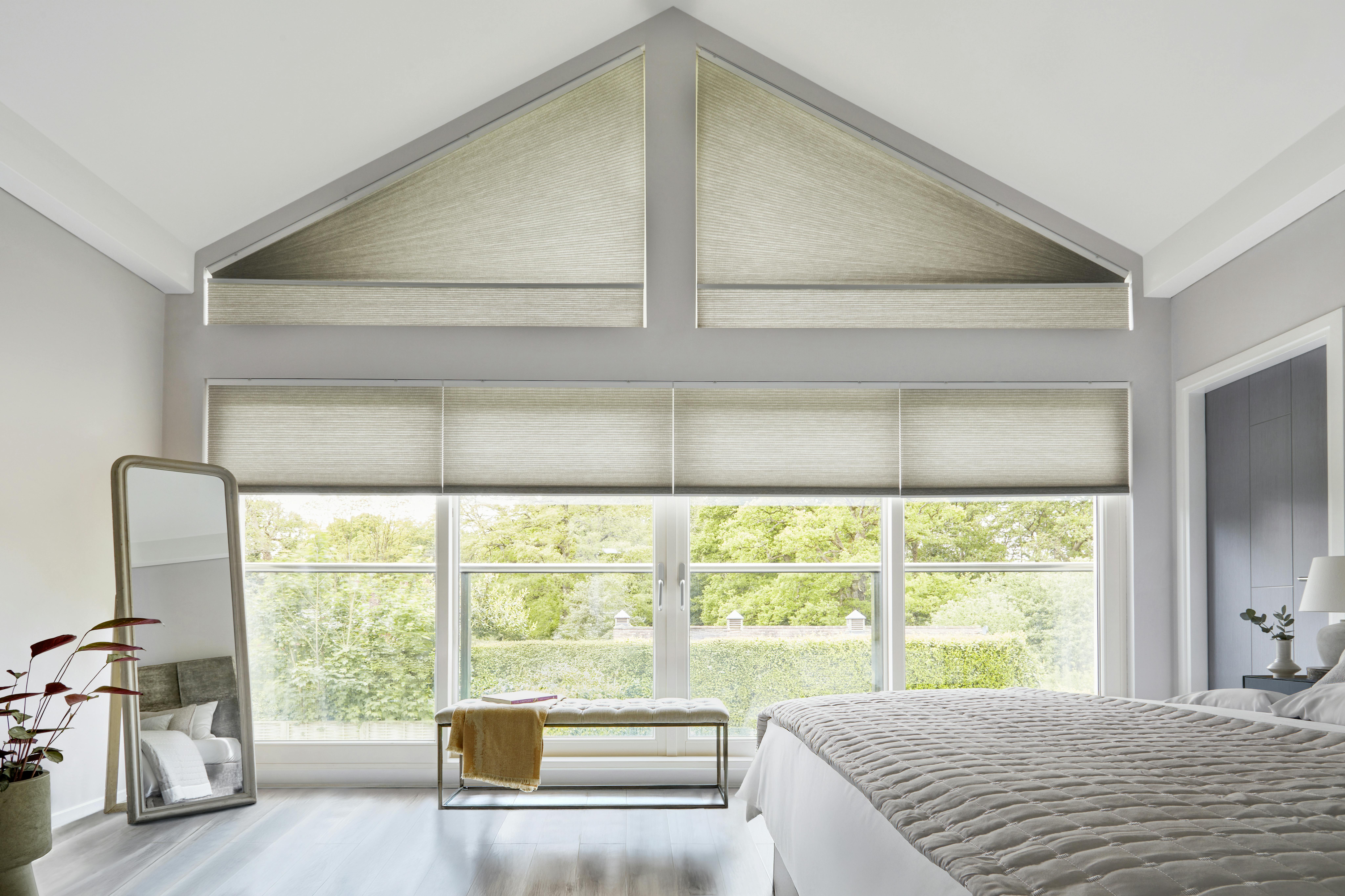 Lichte slaapkamer met crèmekleurige Duette® shades op grote ramen