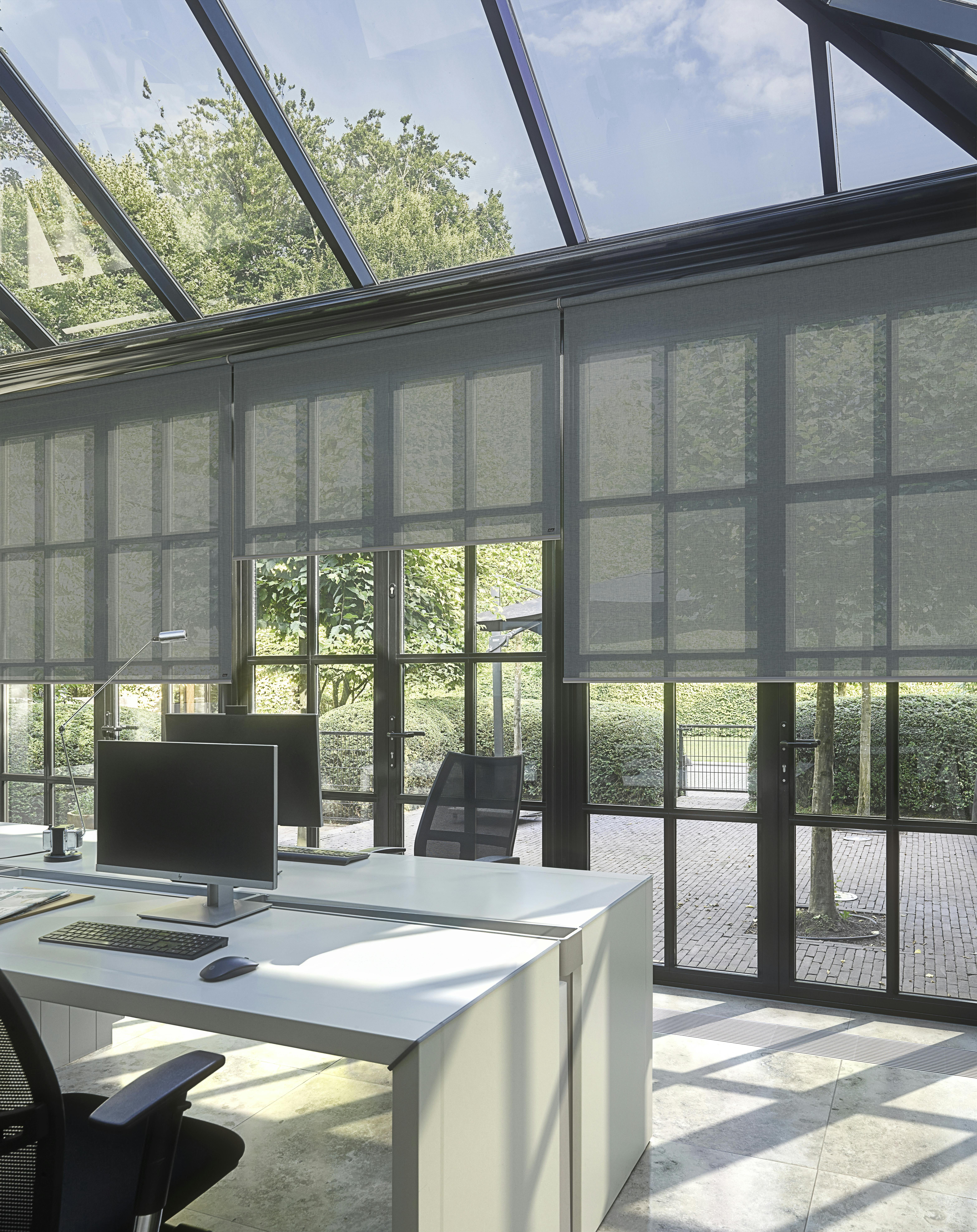 Stores enrouleurs gris dans un bureau à domicile moderne en verre