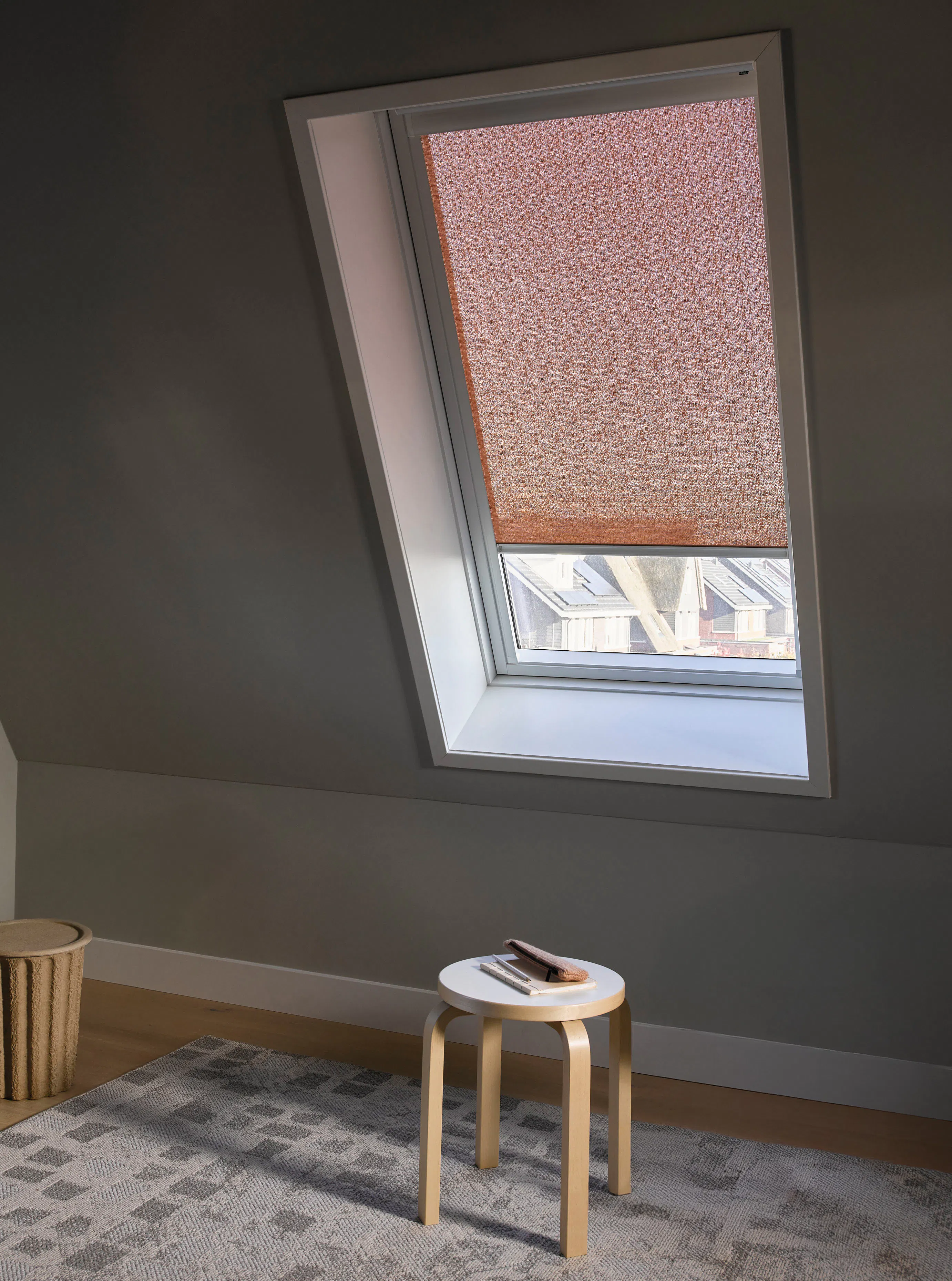 Gedeeltelijk gesloten rode rolgordijnen op een dakraam