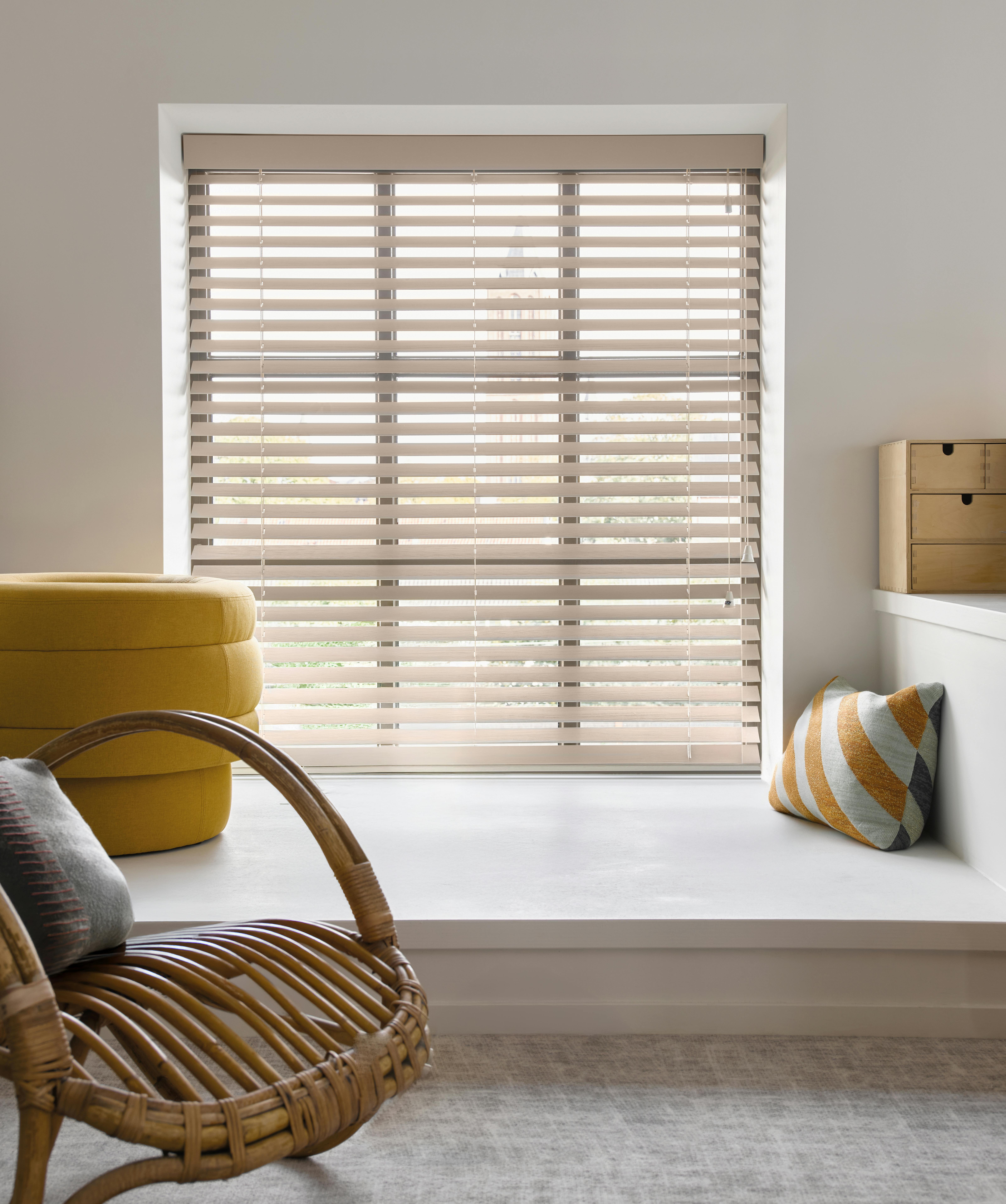 Light brown wood blinds in a semi-open position on a standard window