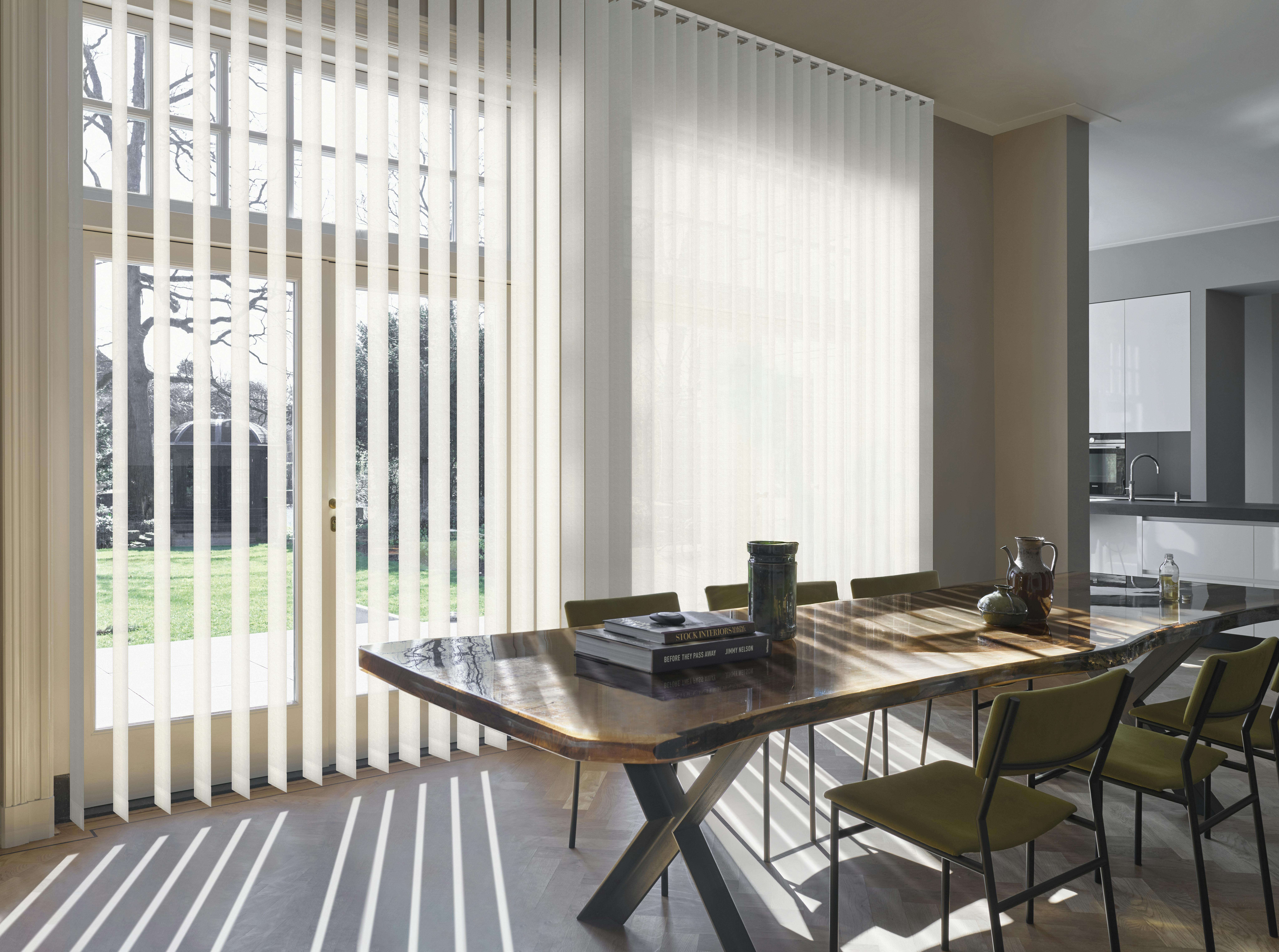 White vertical blinds on french doors and large windows in a dining room