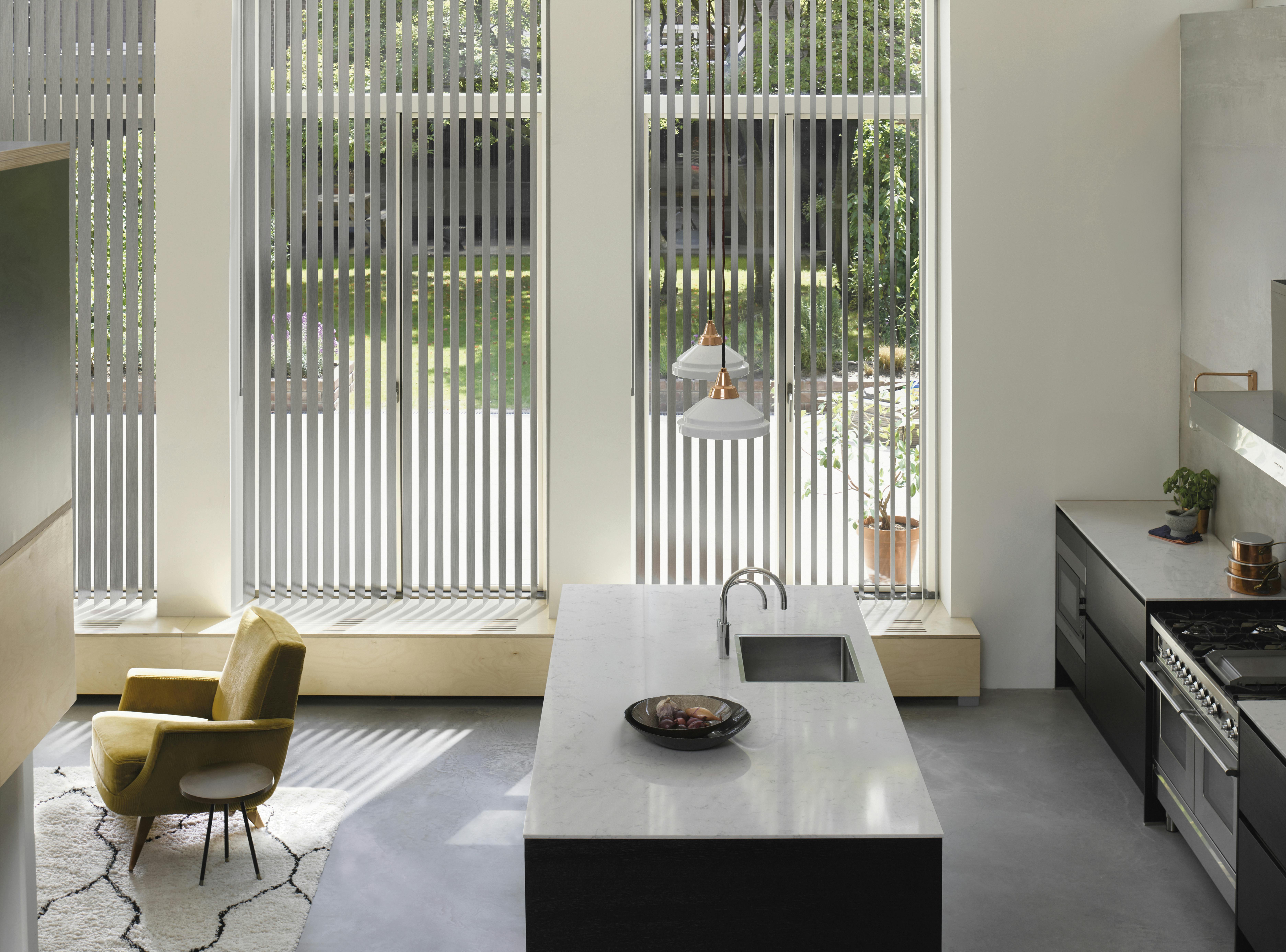 Grå lamellgardiner i store vinduer i et romslig kjøkken og spisestue.