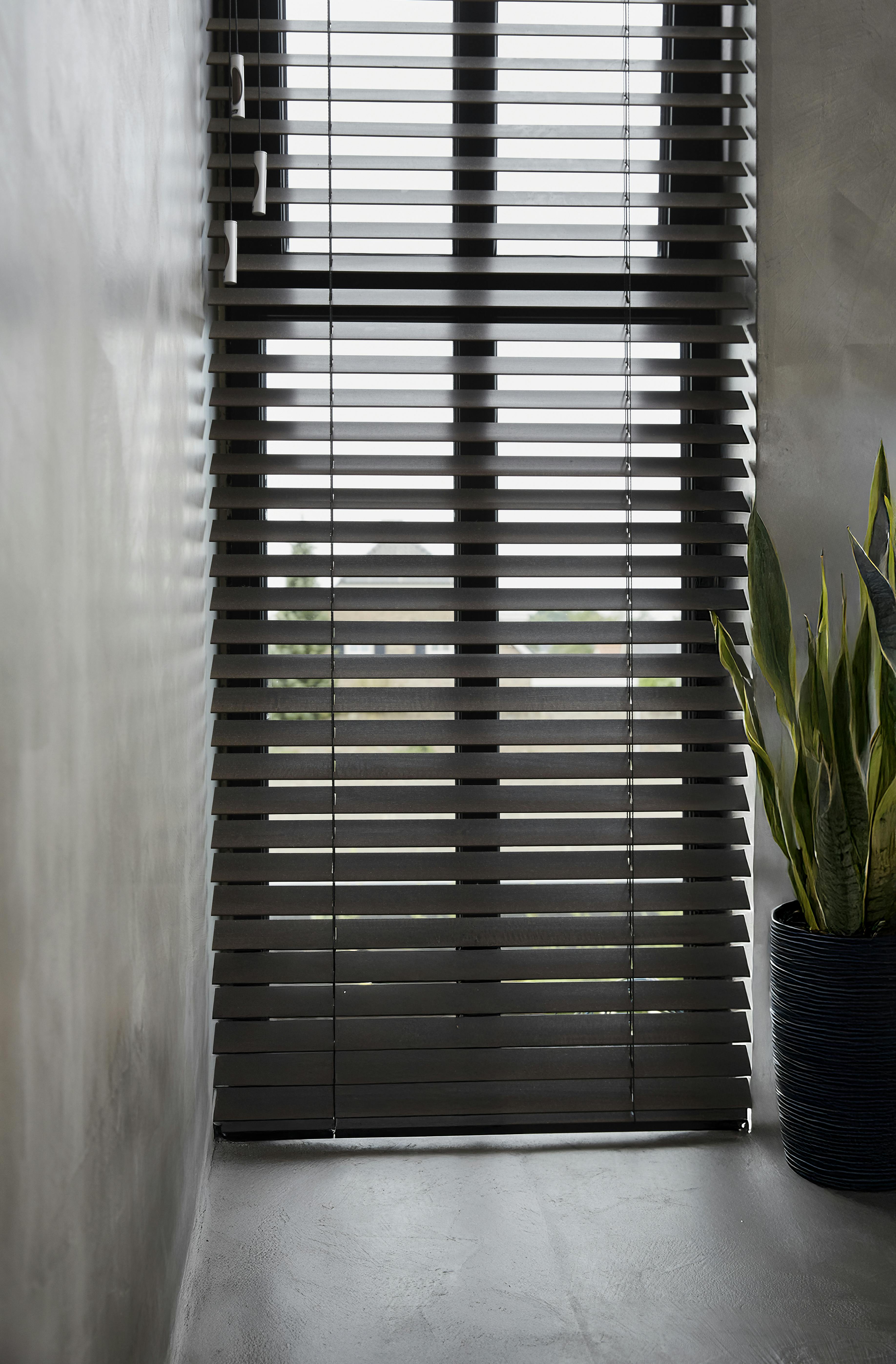 Donkerbruine houten jaloezieën op een raam in de gang