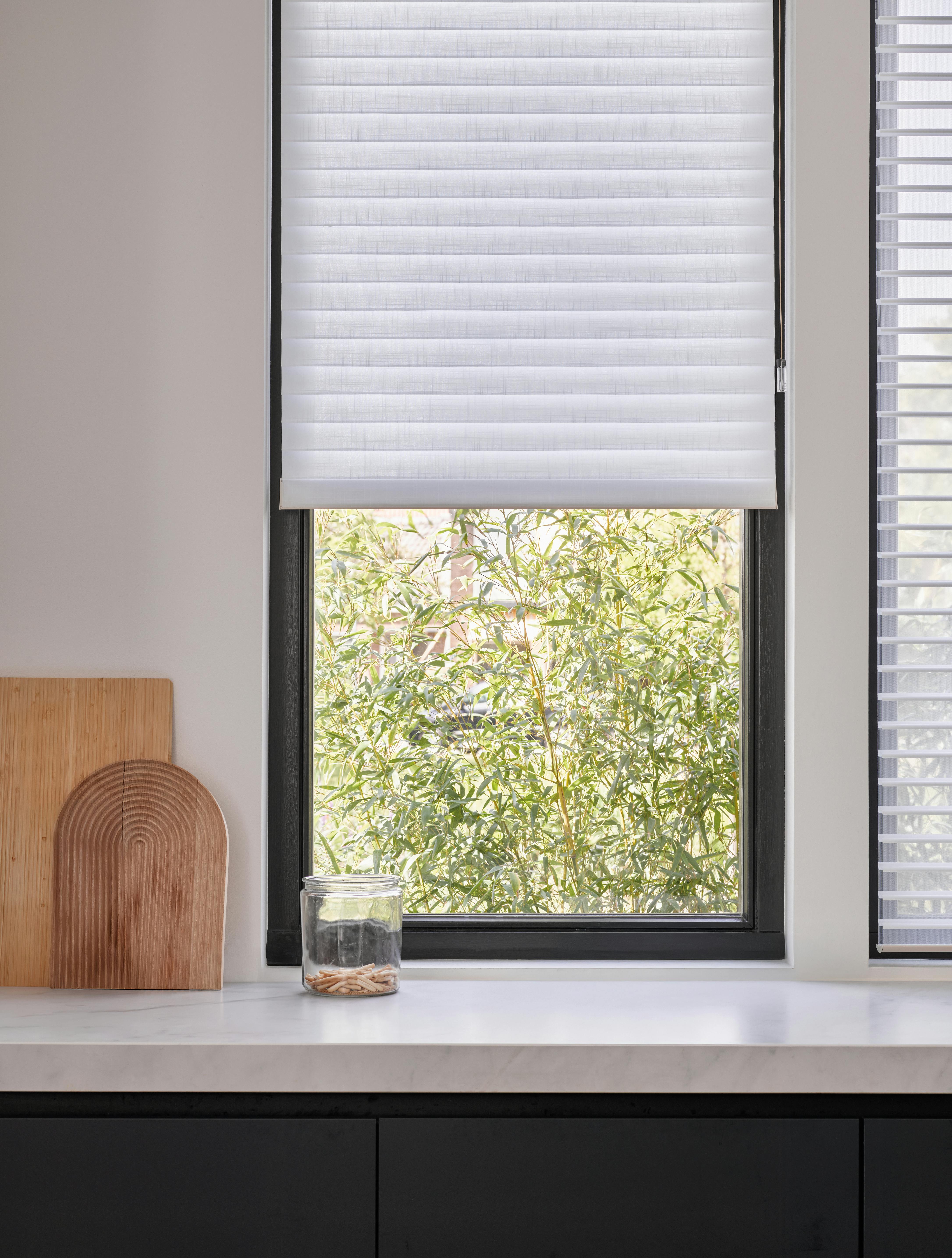 Closeup of a white silhouette shades on a kitchen window 