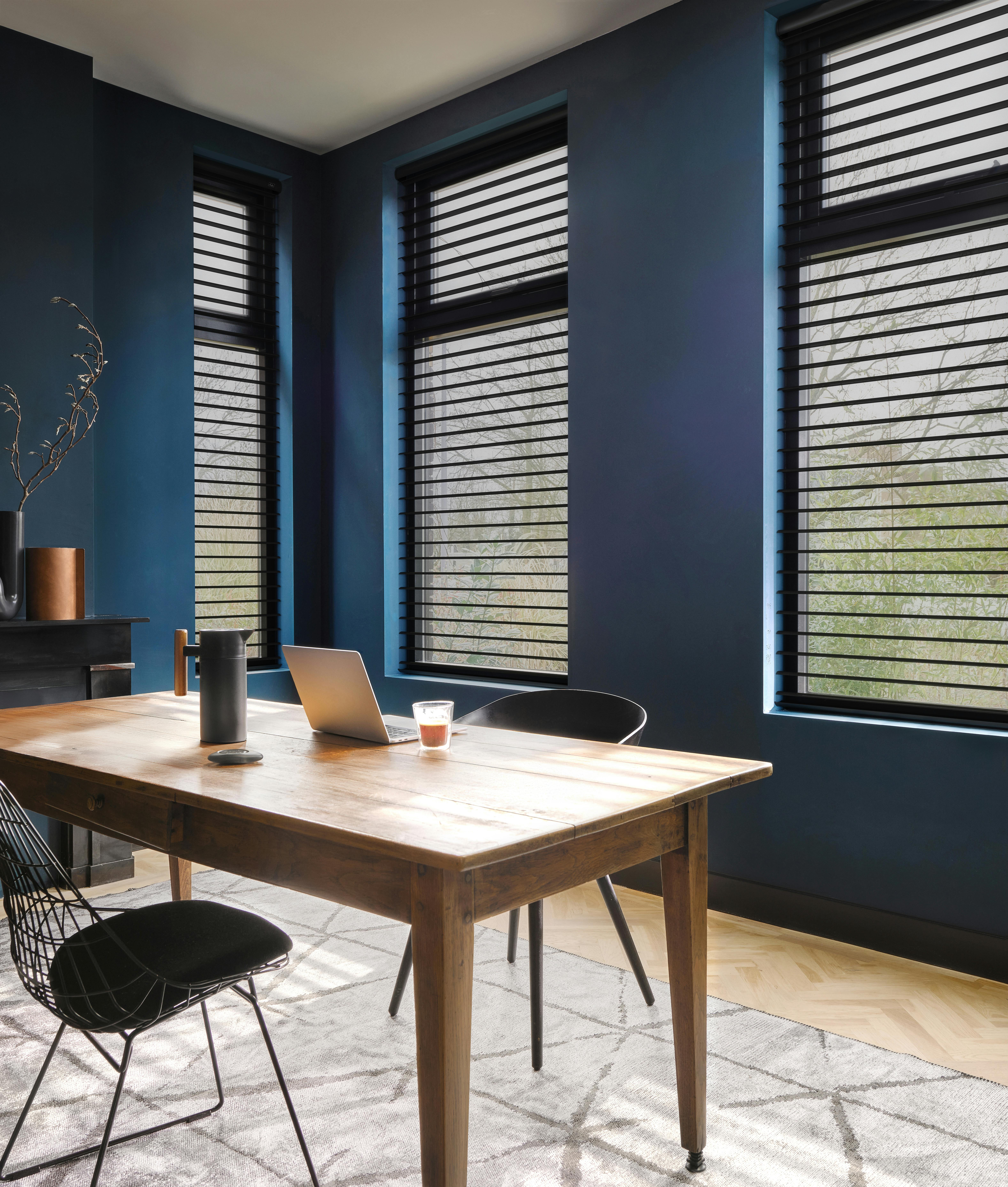 Black silhouette shades on windows in a blue home office