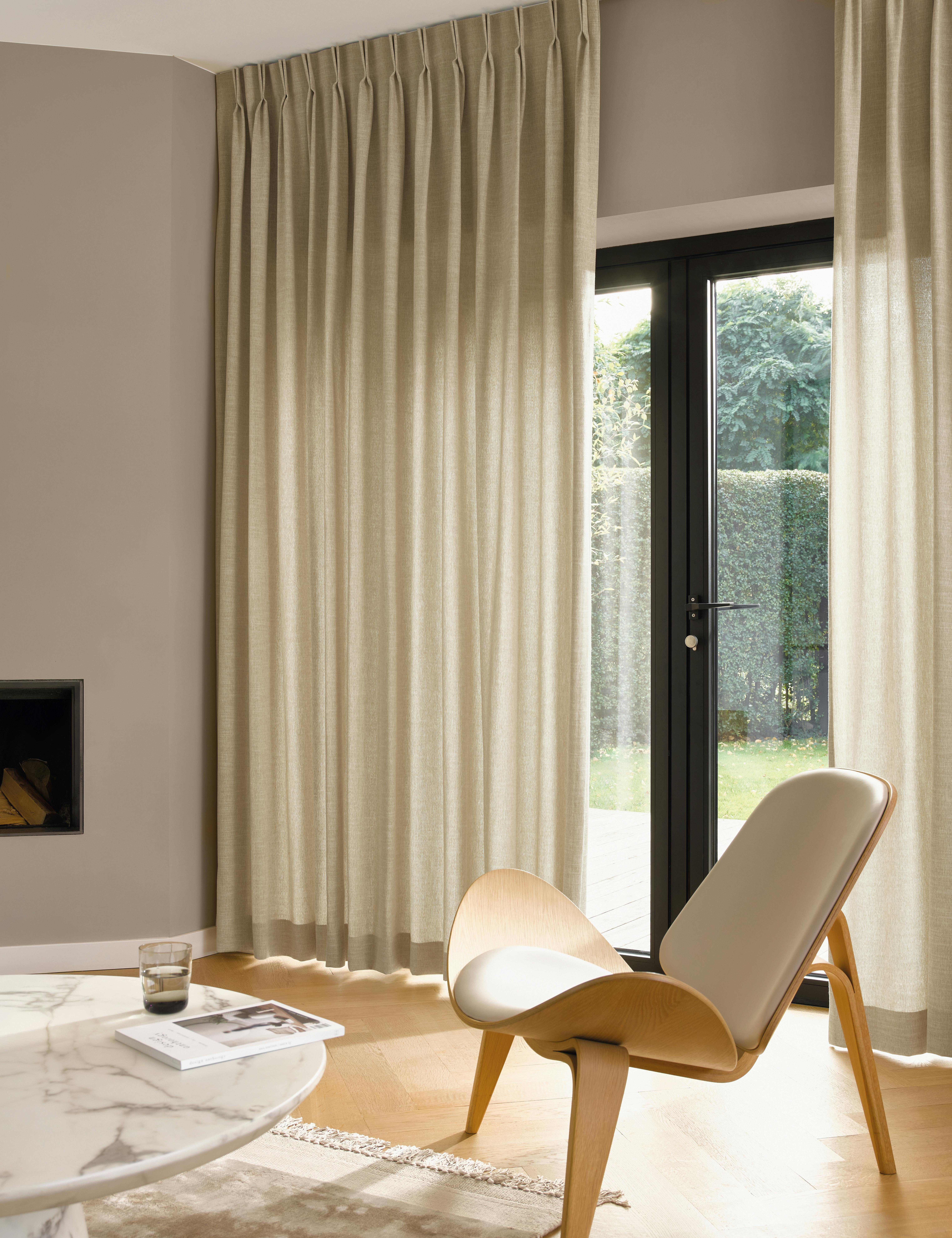 Cream curtains on large windows in a light living room