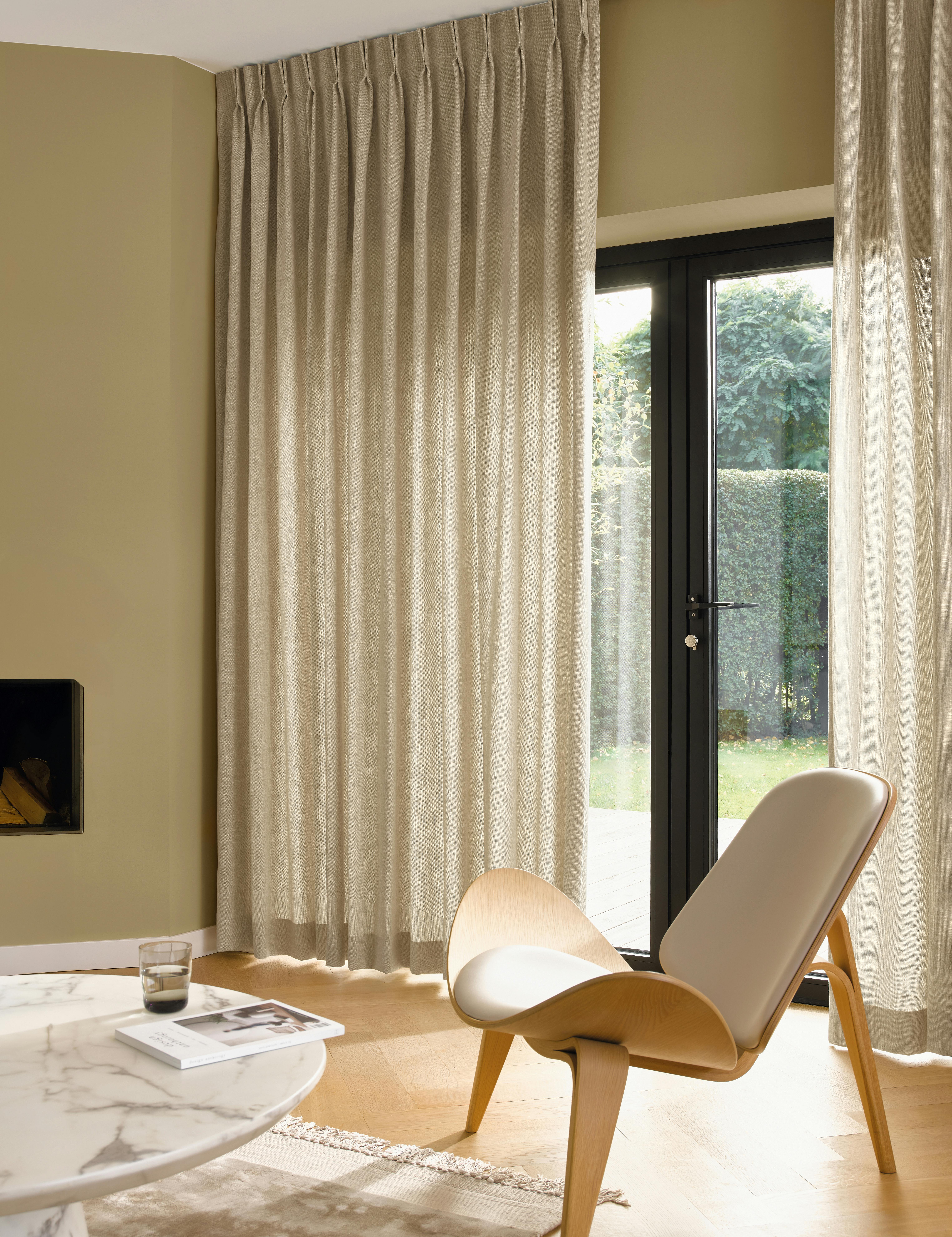 Cream curtains on large windows in a light living room