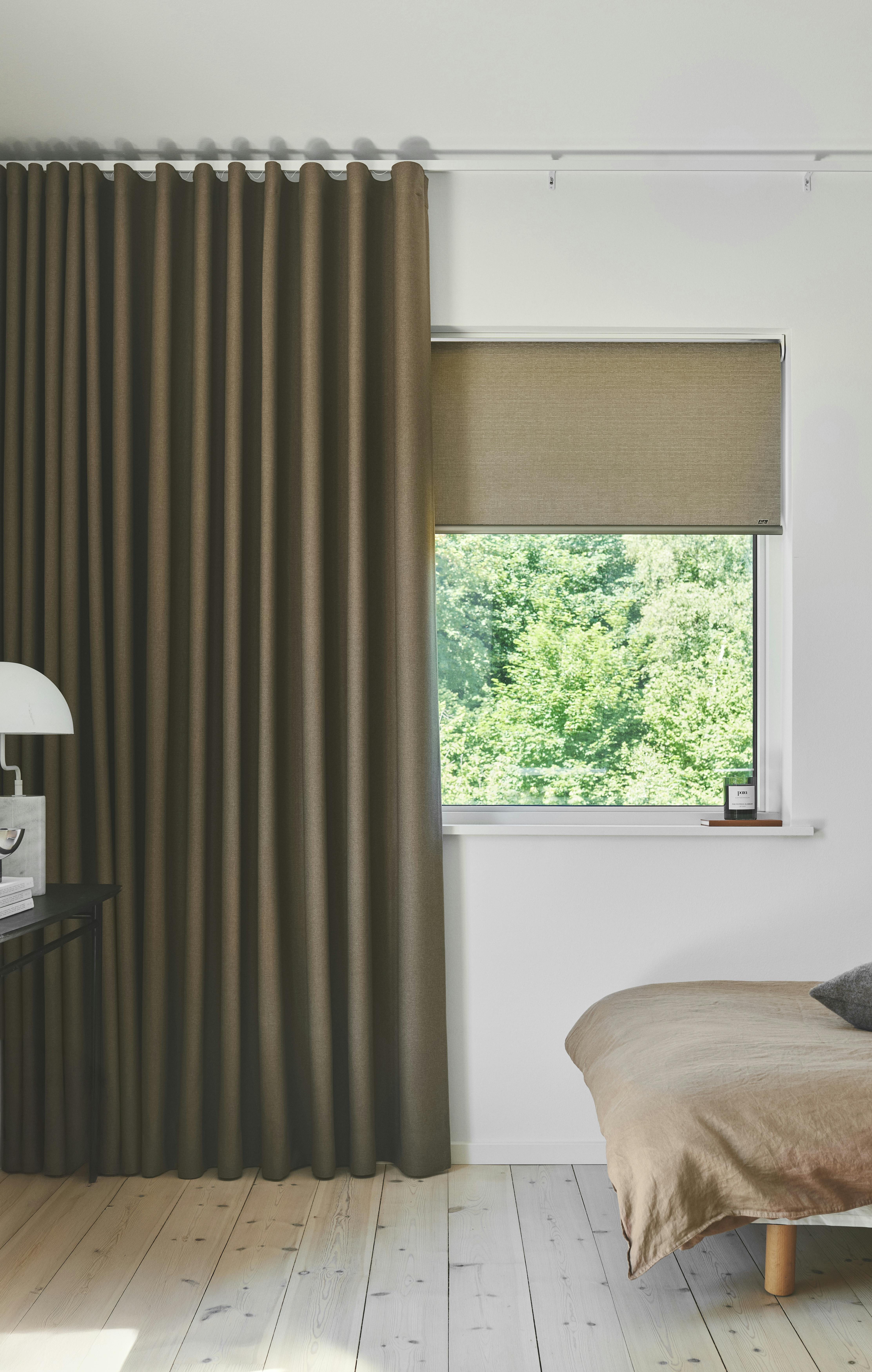 Beige gardinlengder og rullegardin i et lyst soverom