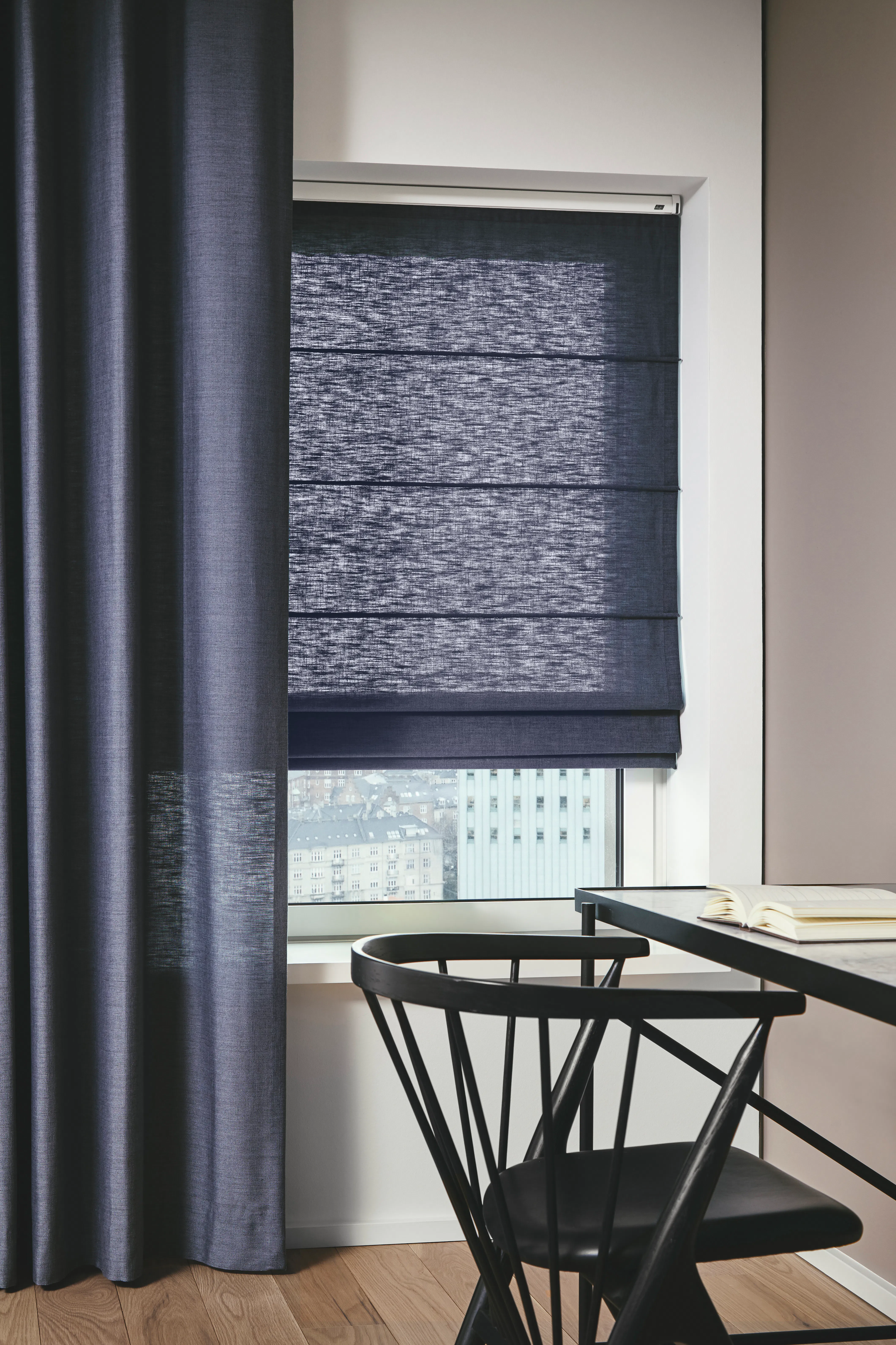 Blauwe gordijnen en gesloten vouwgordijnen voor een raam in een lichte kamer