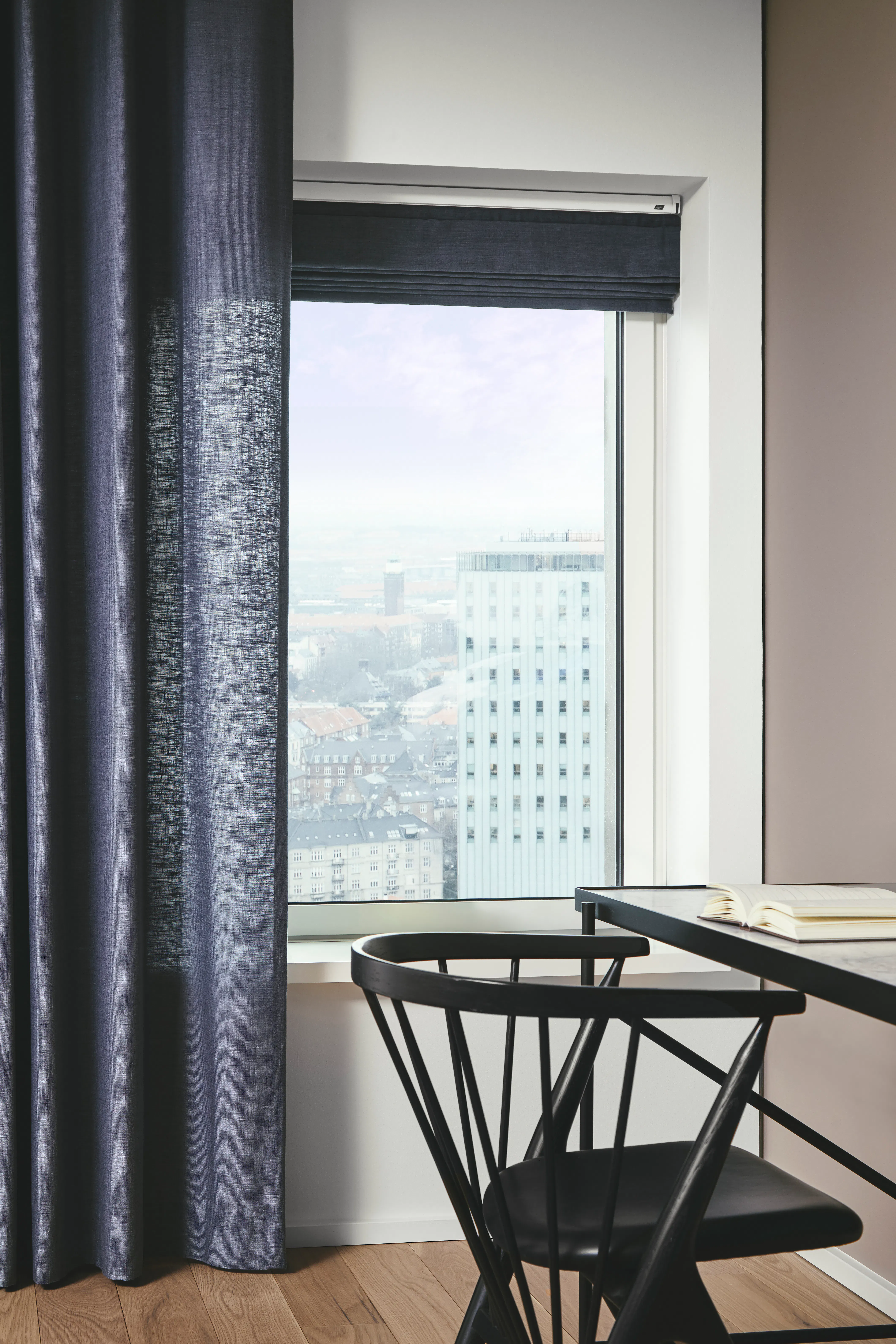 Blue curtains and opened roman blinds on a window in a light room 