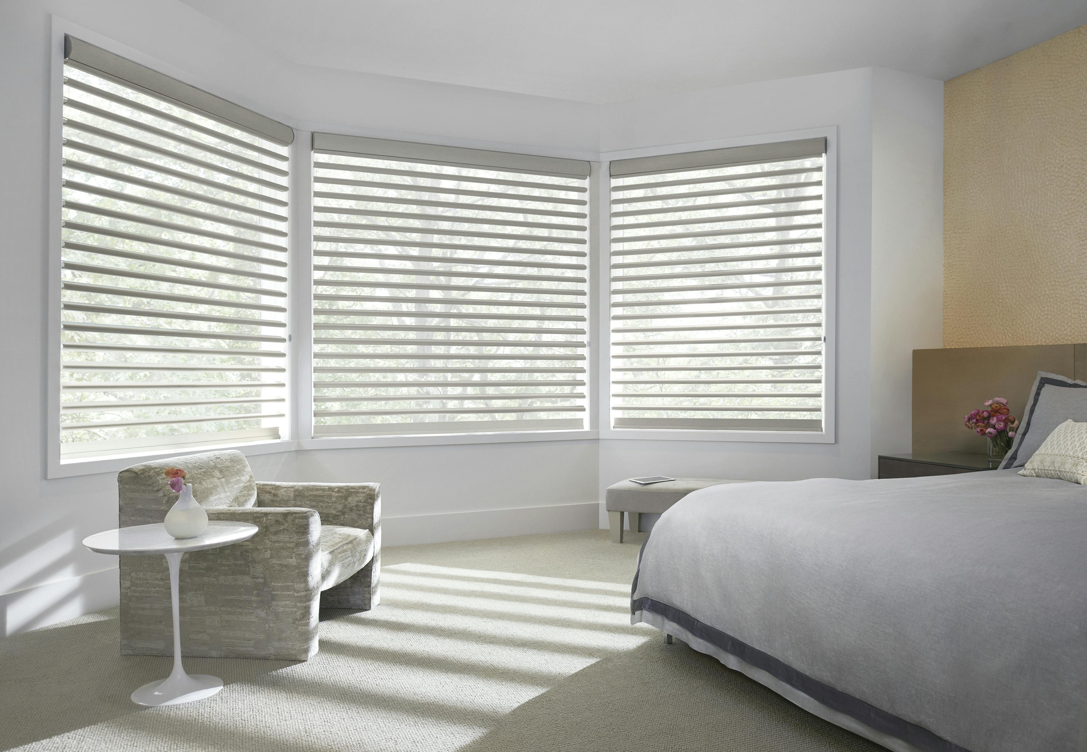 Grey pirouette shades on a conservatorium-style window in a bedroom 