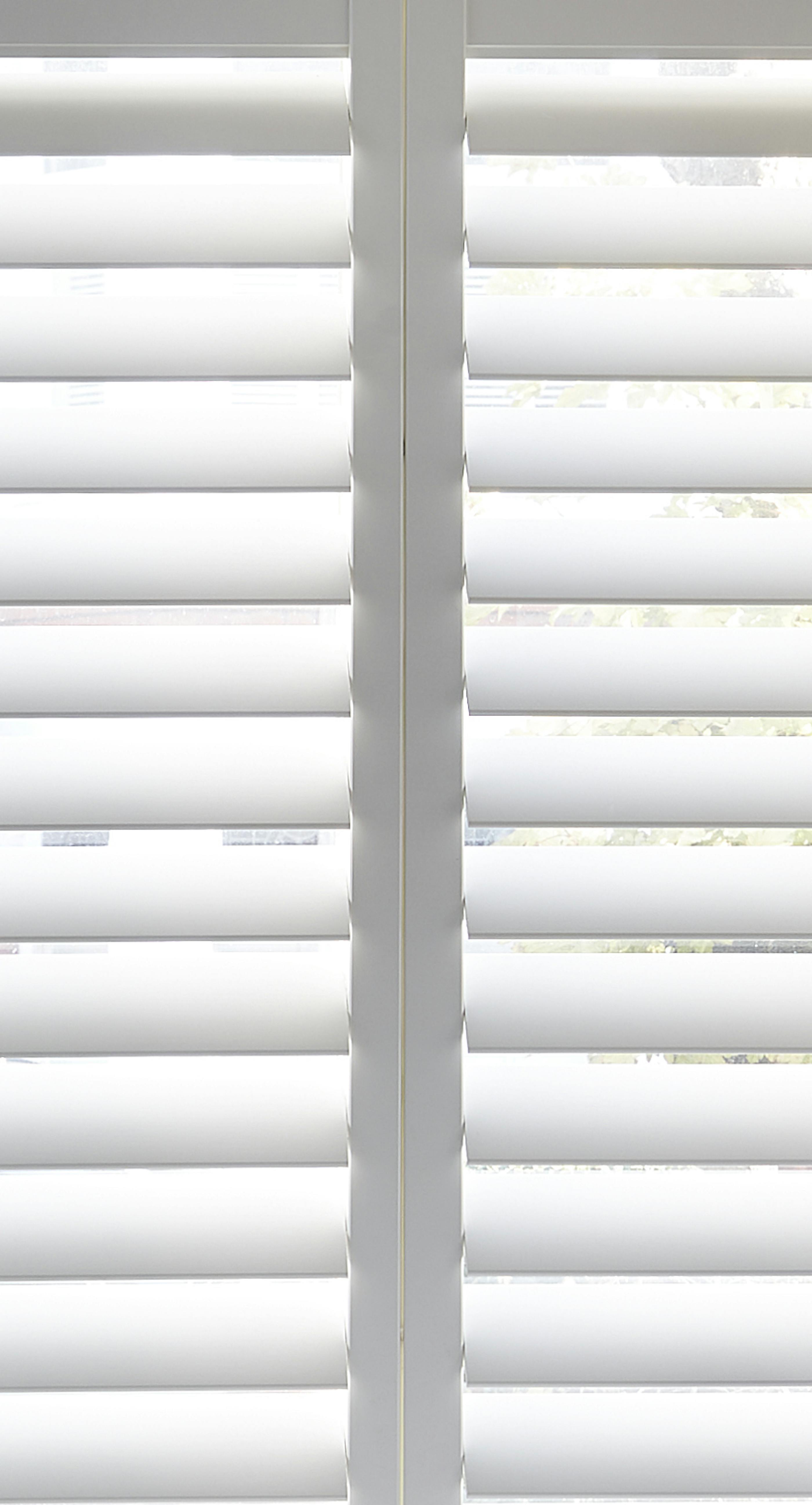Witte, licht geopende shutters op een raam