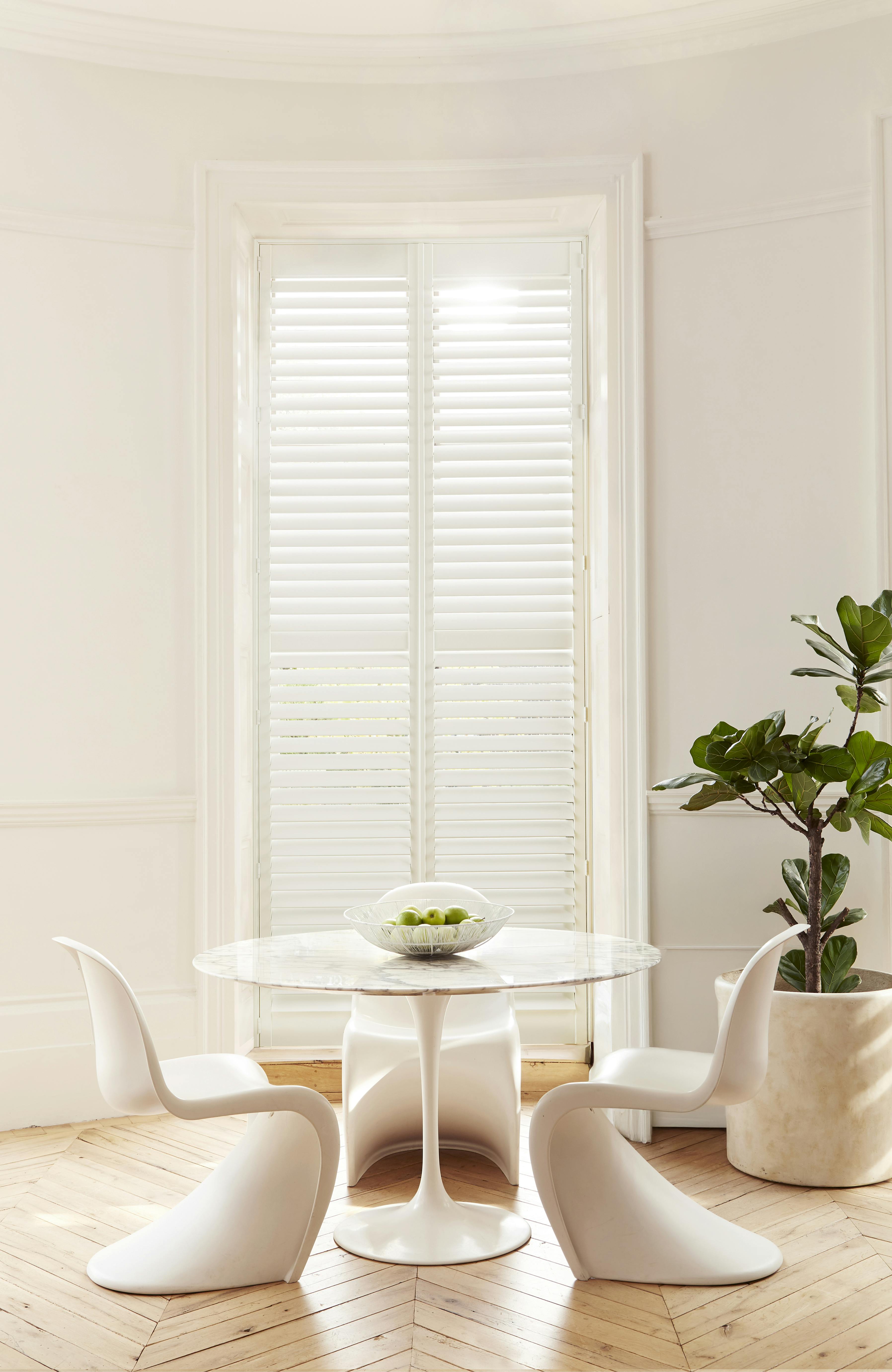 White shutters on a window in a light modern dining area