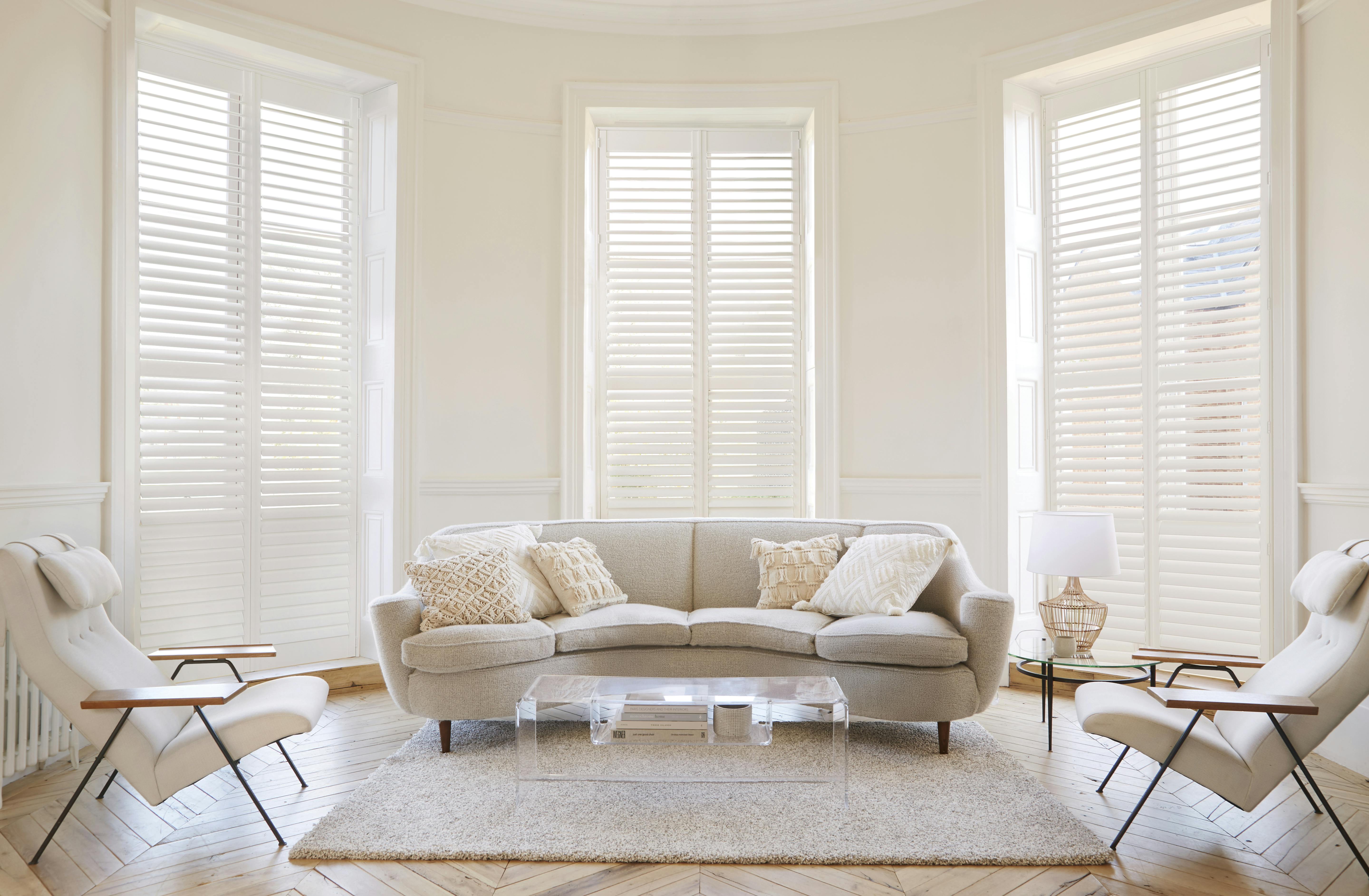 White shutters on windows in a light elegant living room with cream accents
