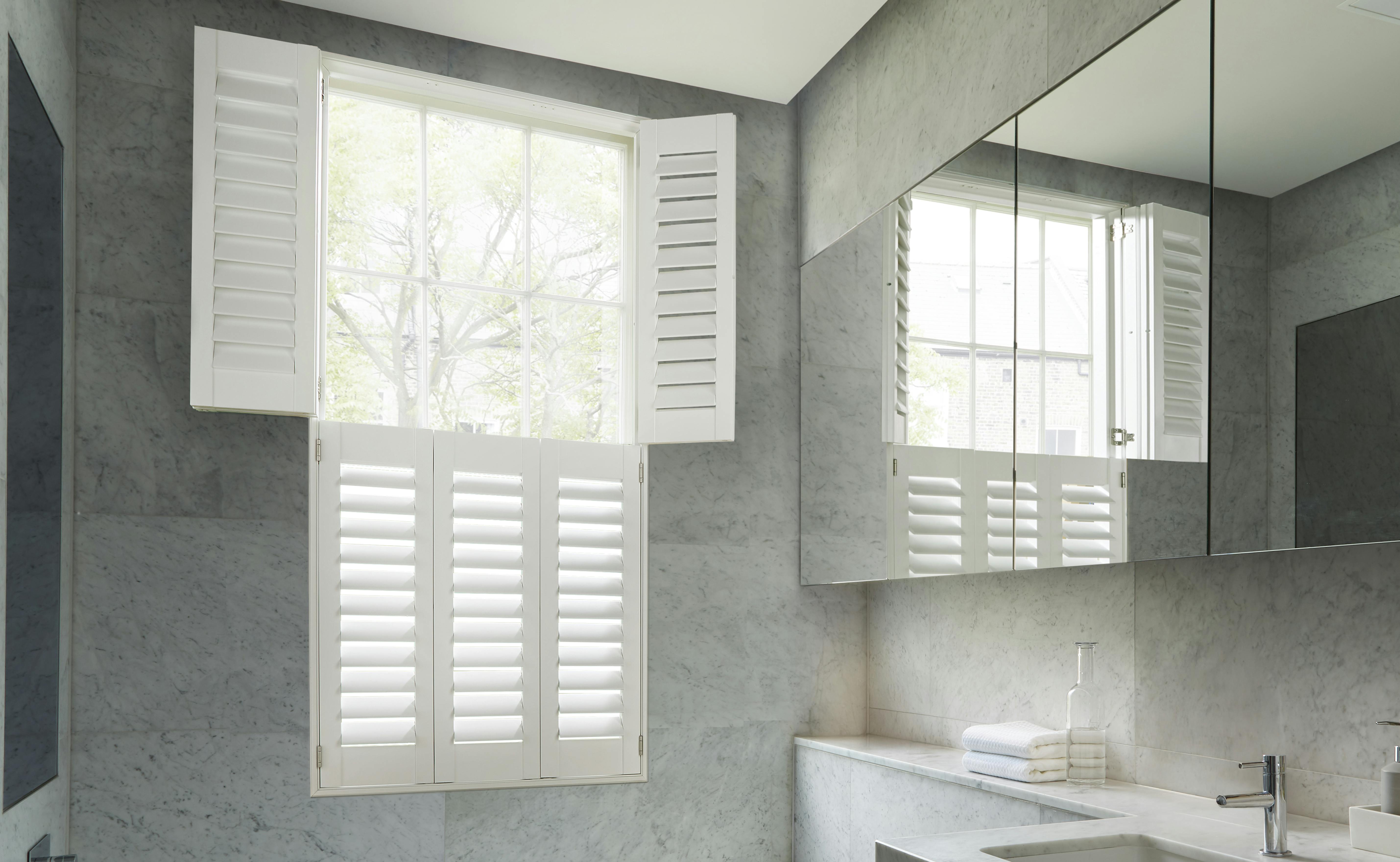 White opened shutters on a window in a light modern bathroom