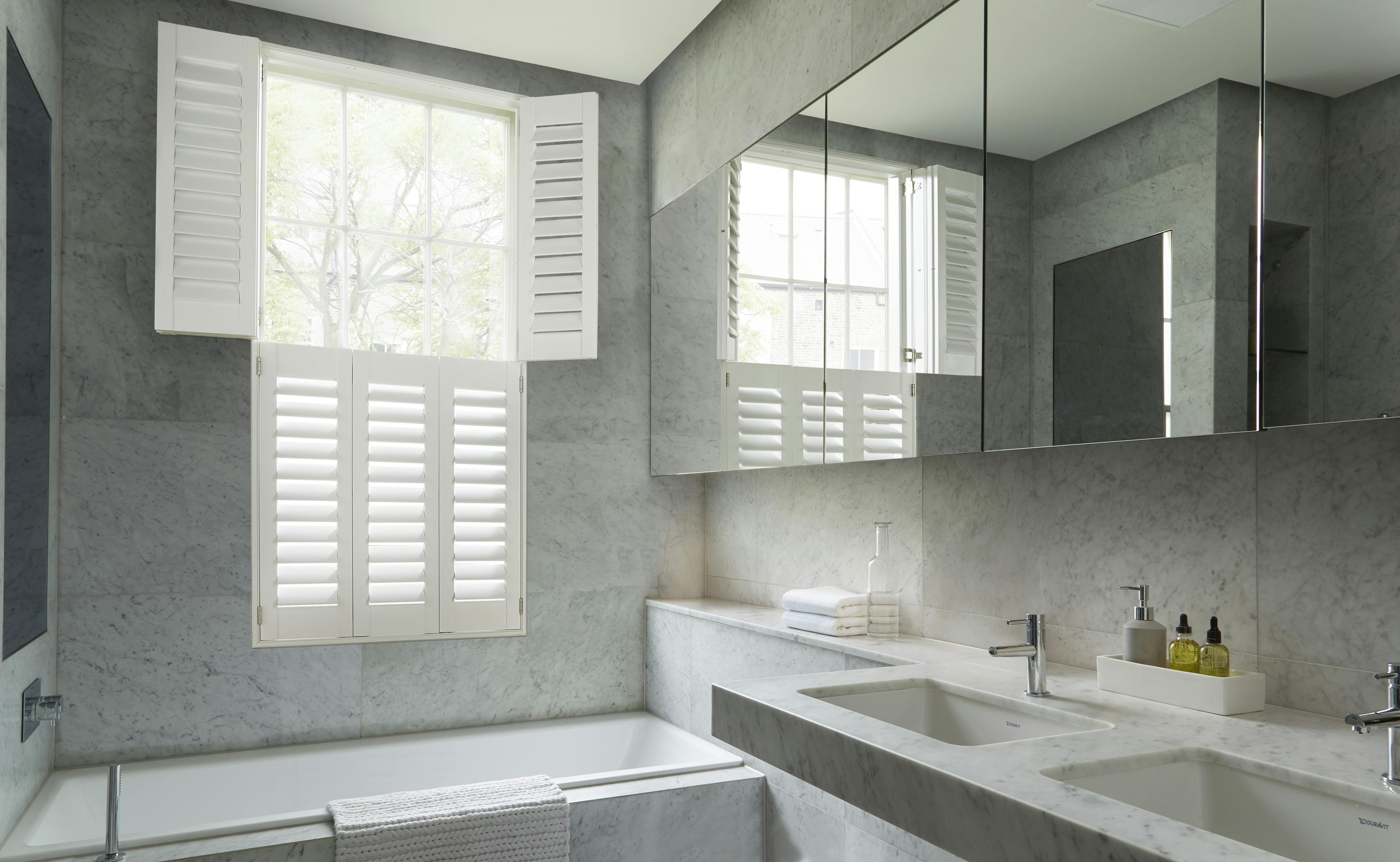 White opened shutters on a window in a light modern bathroom