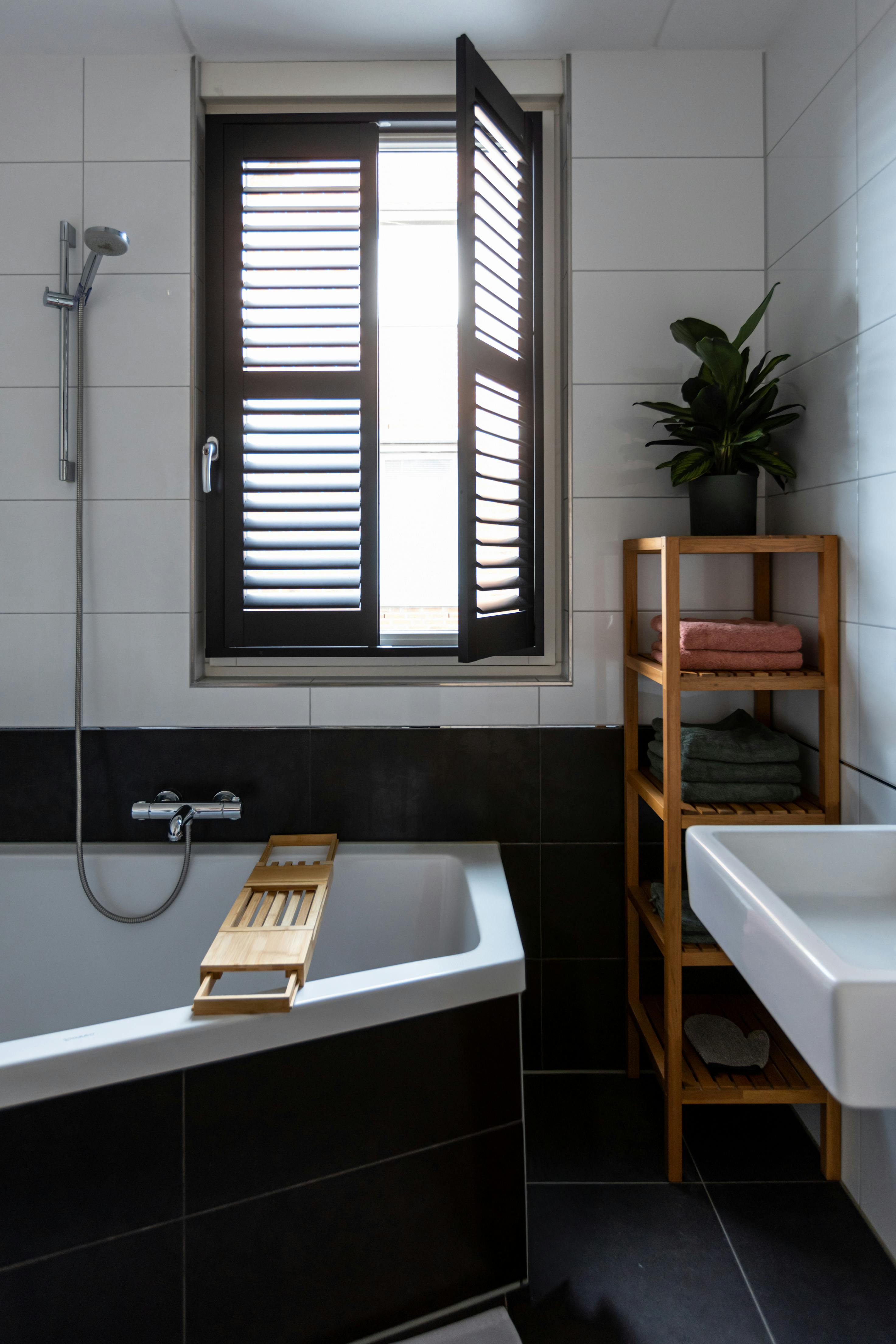 White shutters on a window with a brown frame in a light bathroom
