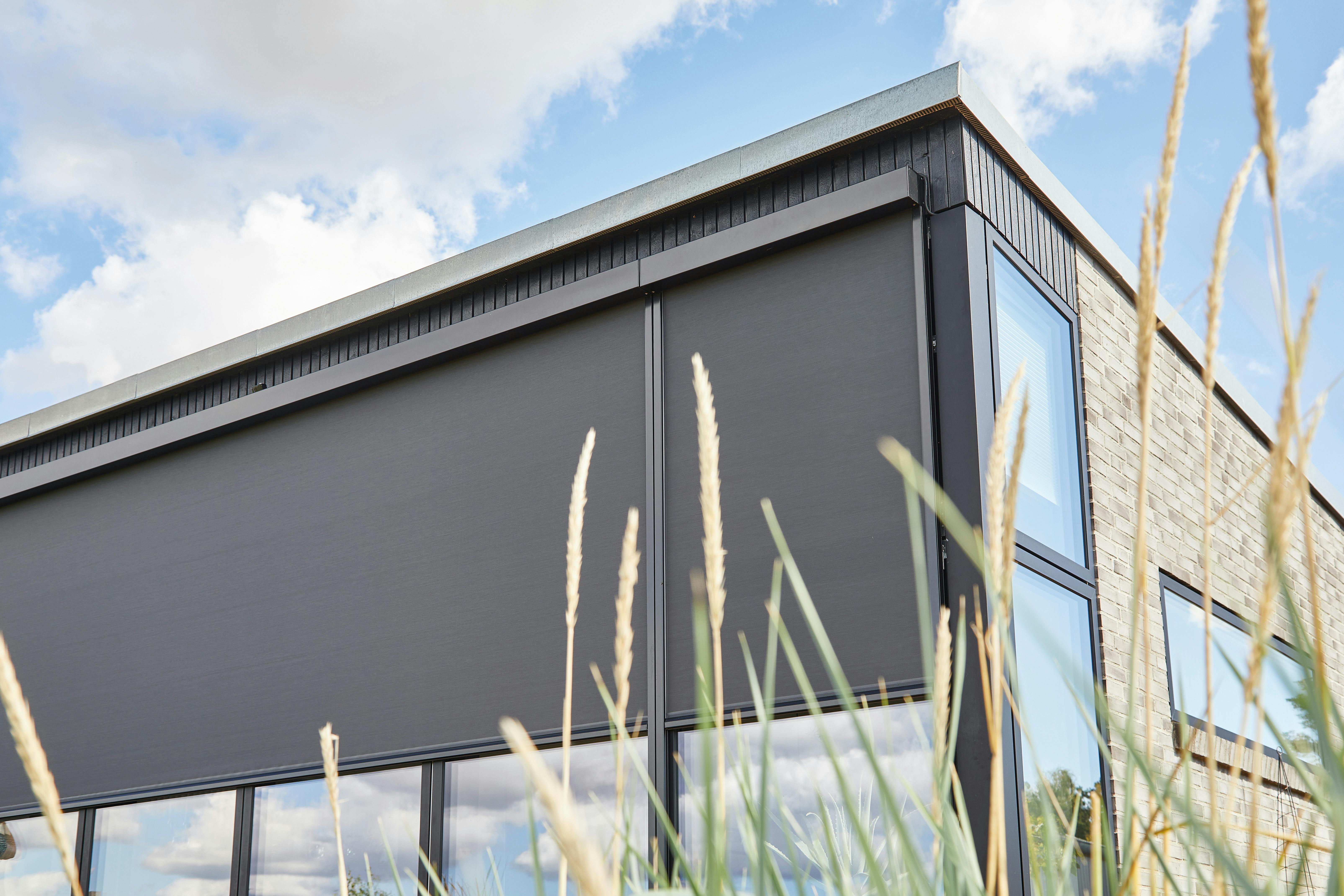 Grey external screens in large windows on a glass house 