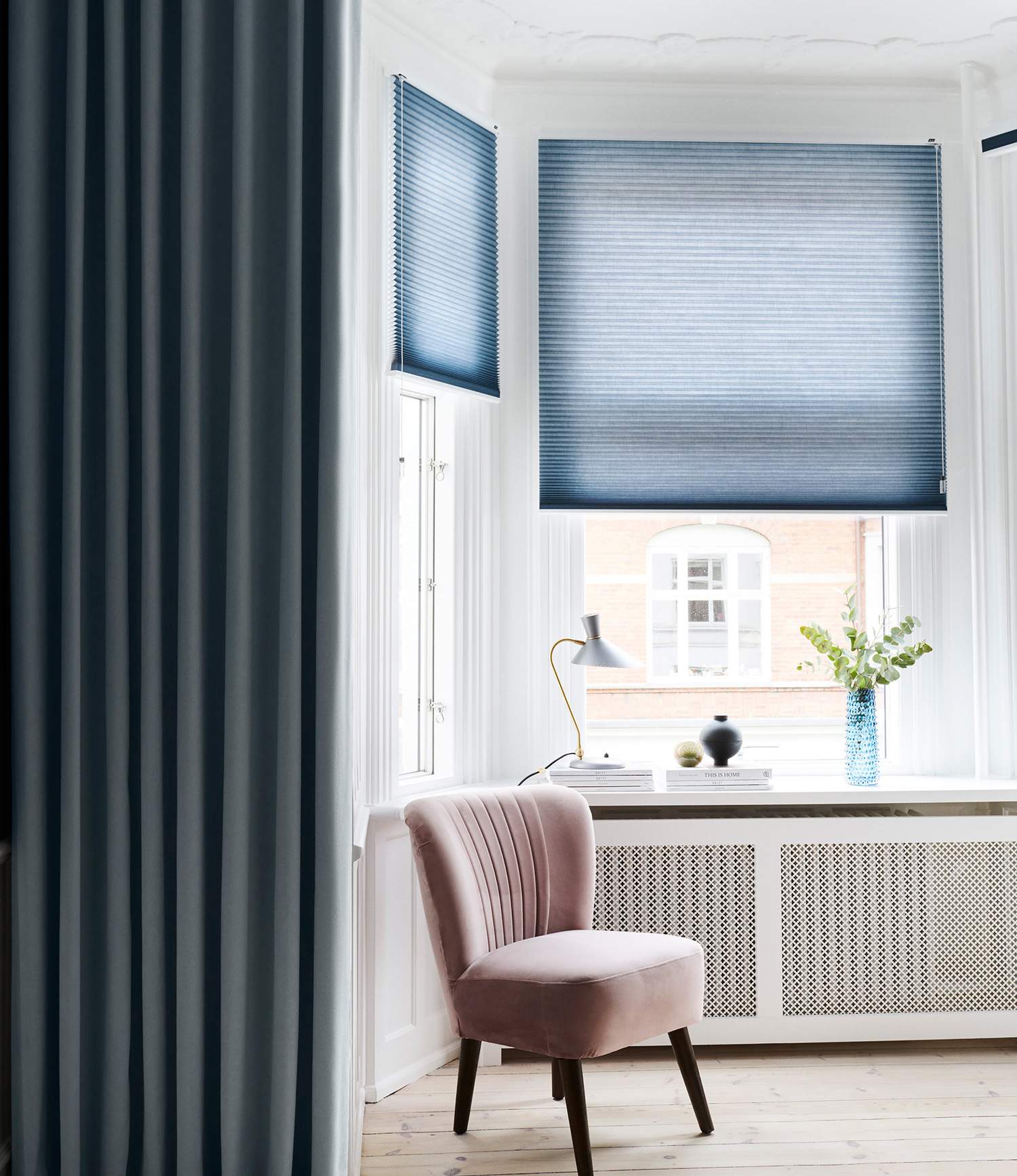 Blue duette shades layered with dark blue curtains in a bay window area