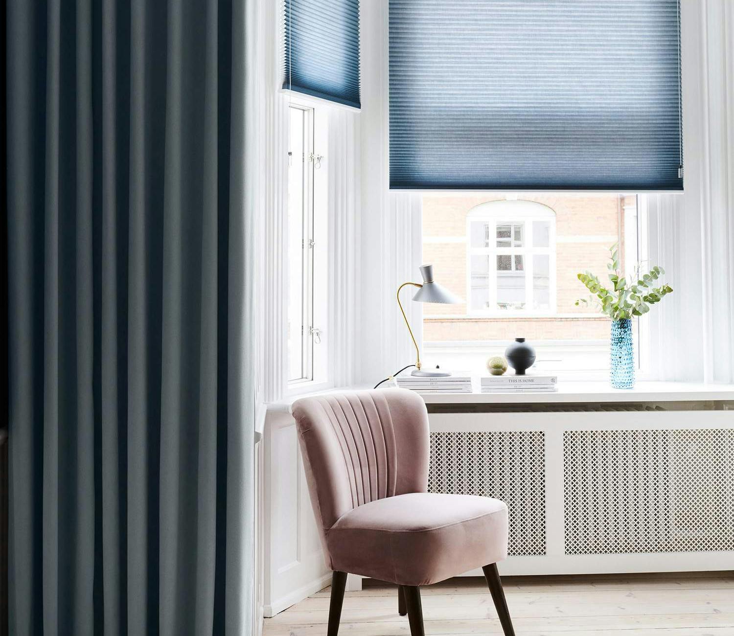 Blue duette shades layered with dark blue curtains in a bay window area