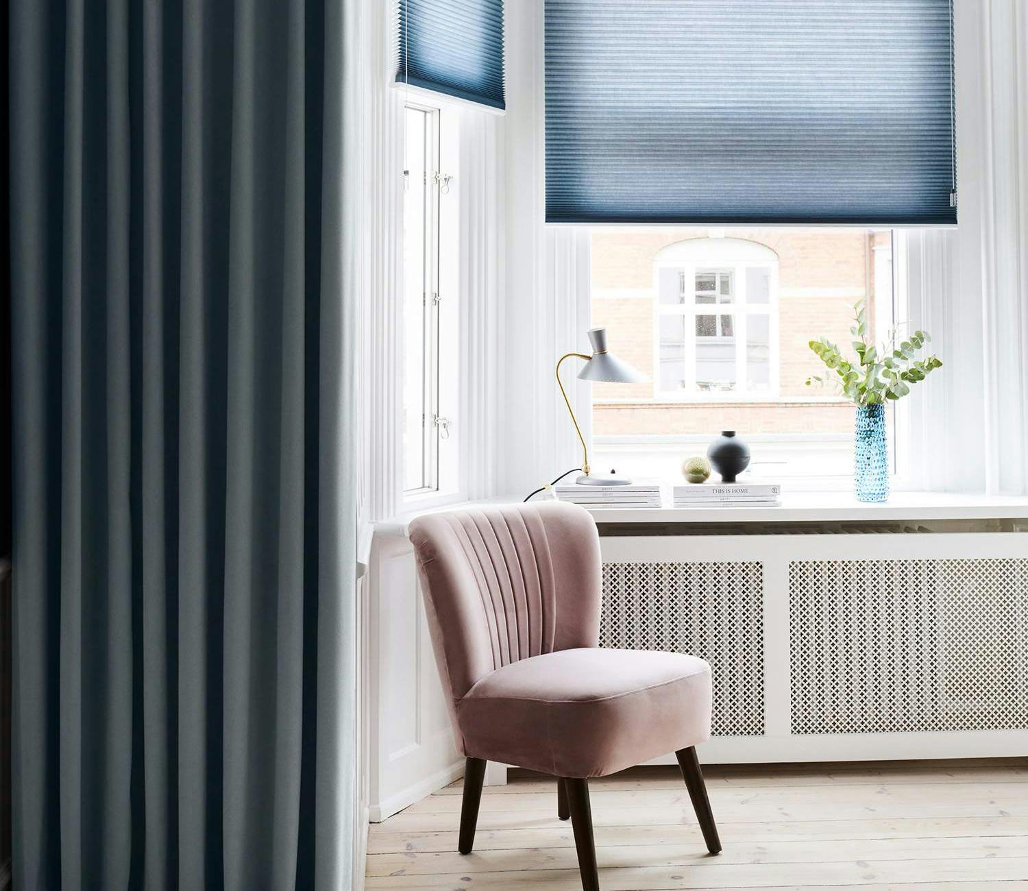 Blue duette shades layered with dark blue curtains in a bay window area
