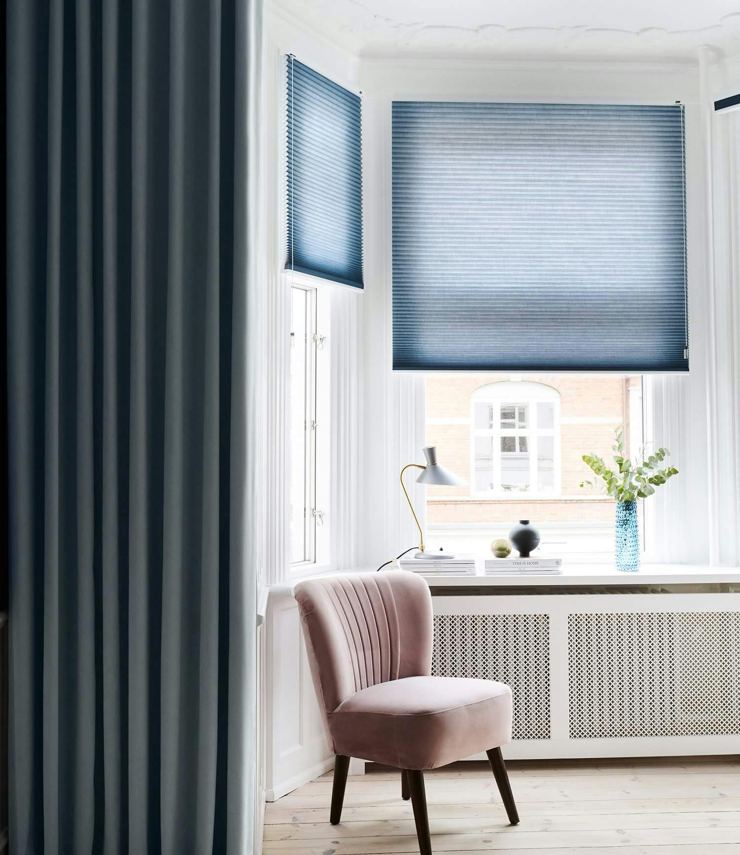 Blue duette shades layered with dark blue curtains in a bay window area