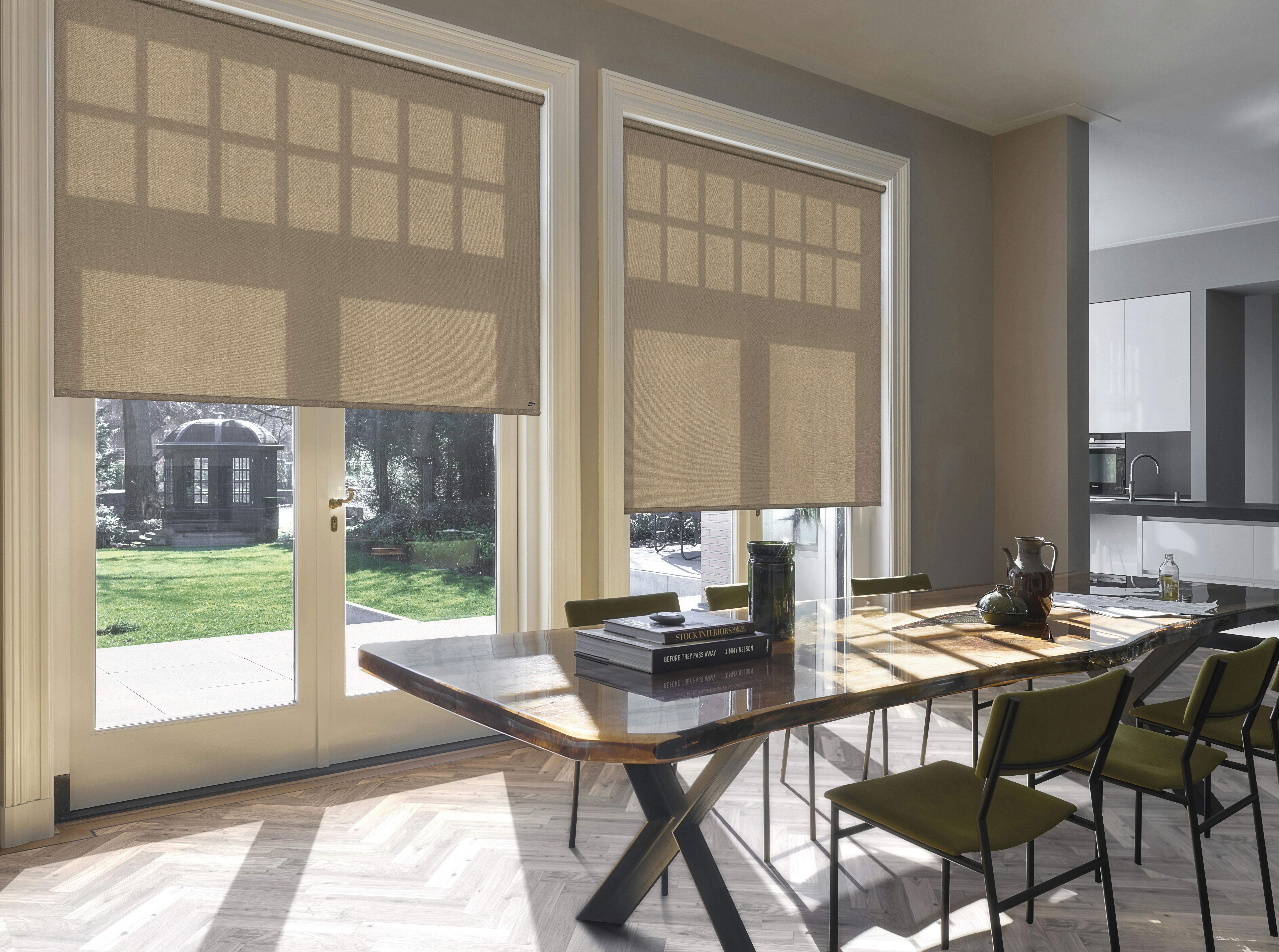 Beige rullegardiner på store vinduer og terrassedør i en lys spisestue