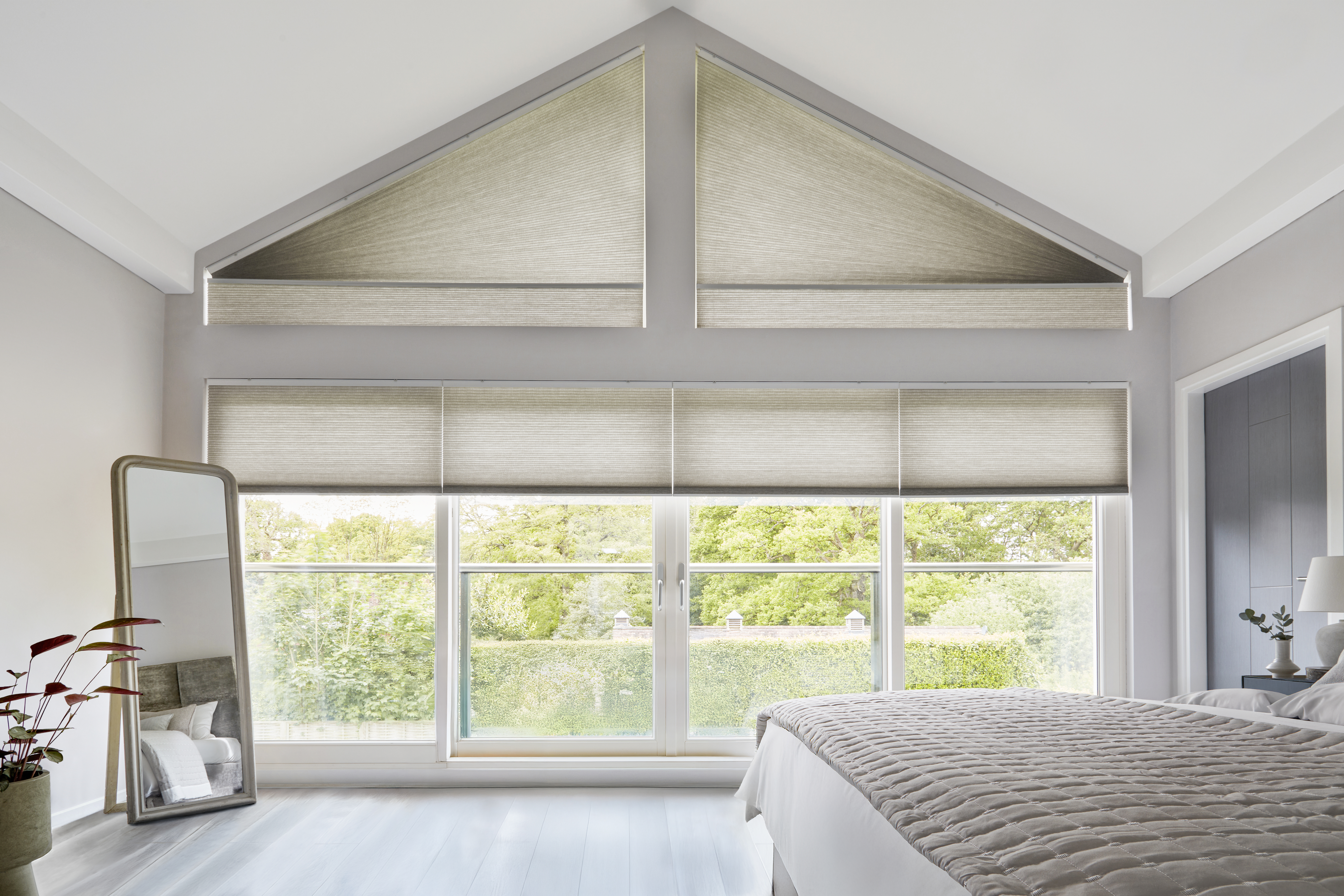 Crèmekleurige Duette® shades op grote ramen en een gevelraam in een woonkamer 