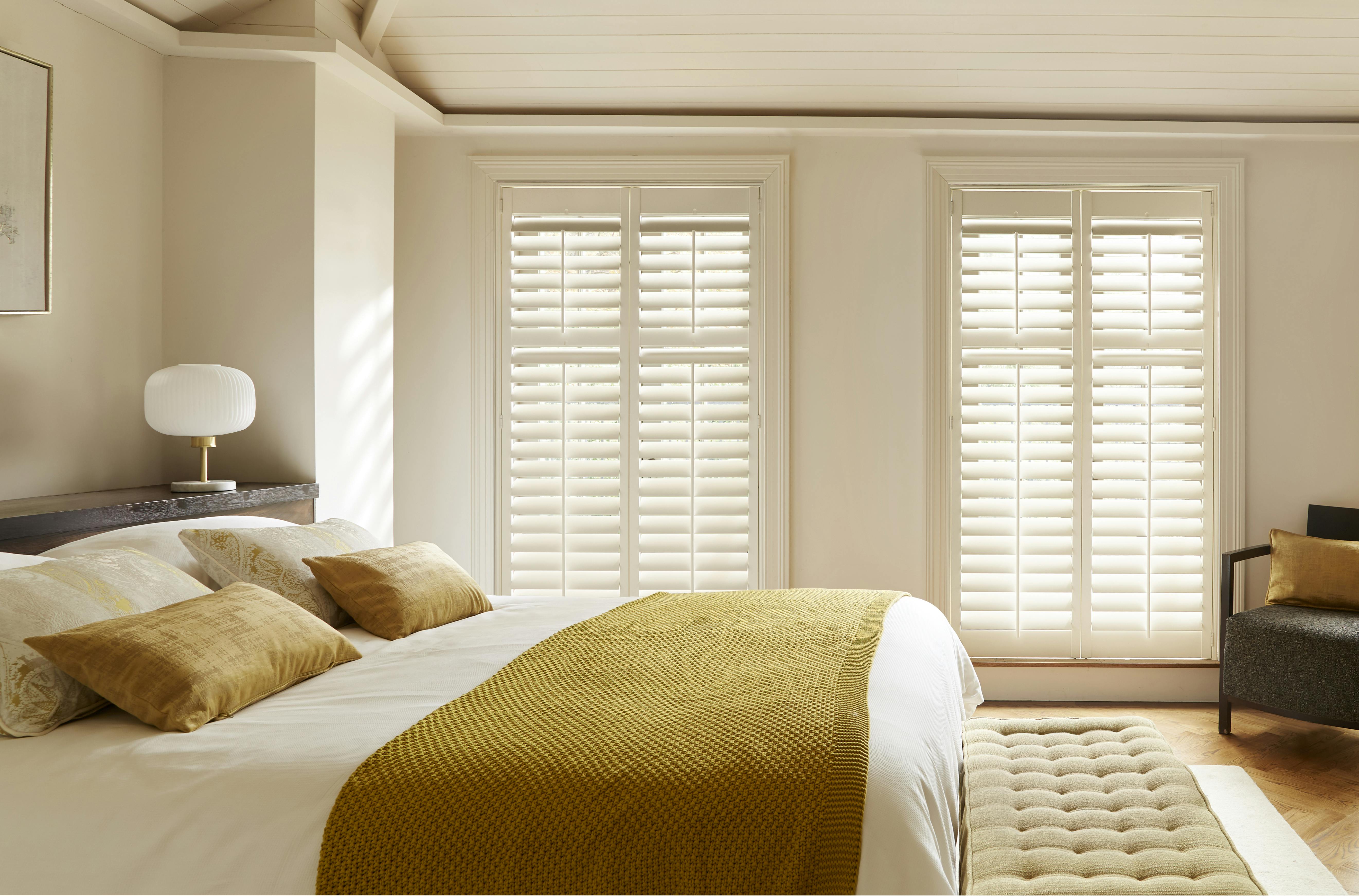 Full-height white shutters in a bedroom