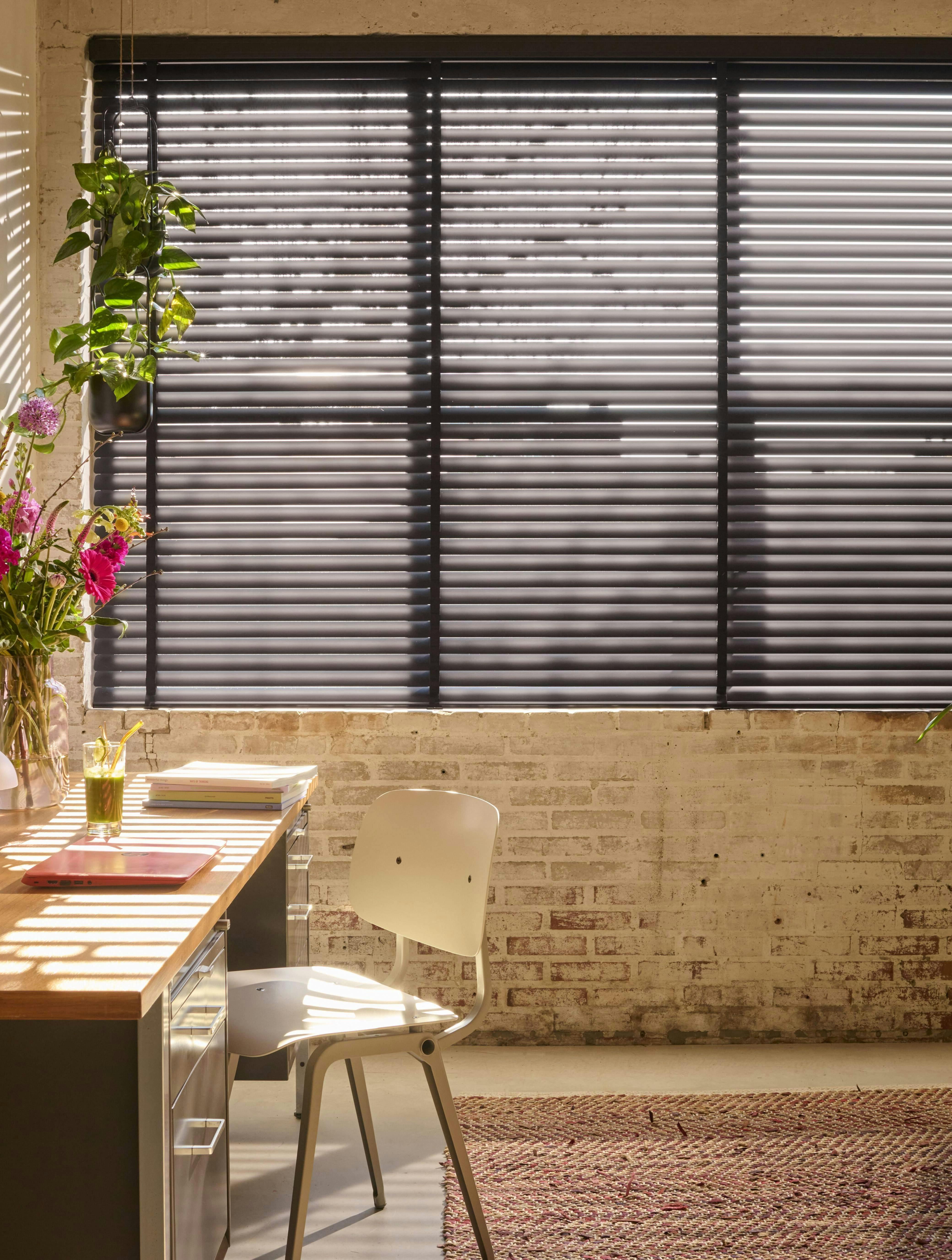 Zwarte horizontale jaloezieën van Luxaflex® in thuiskantoor met veel planten