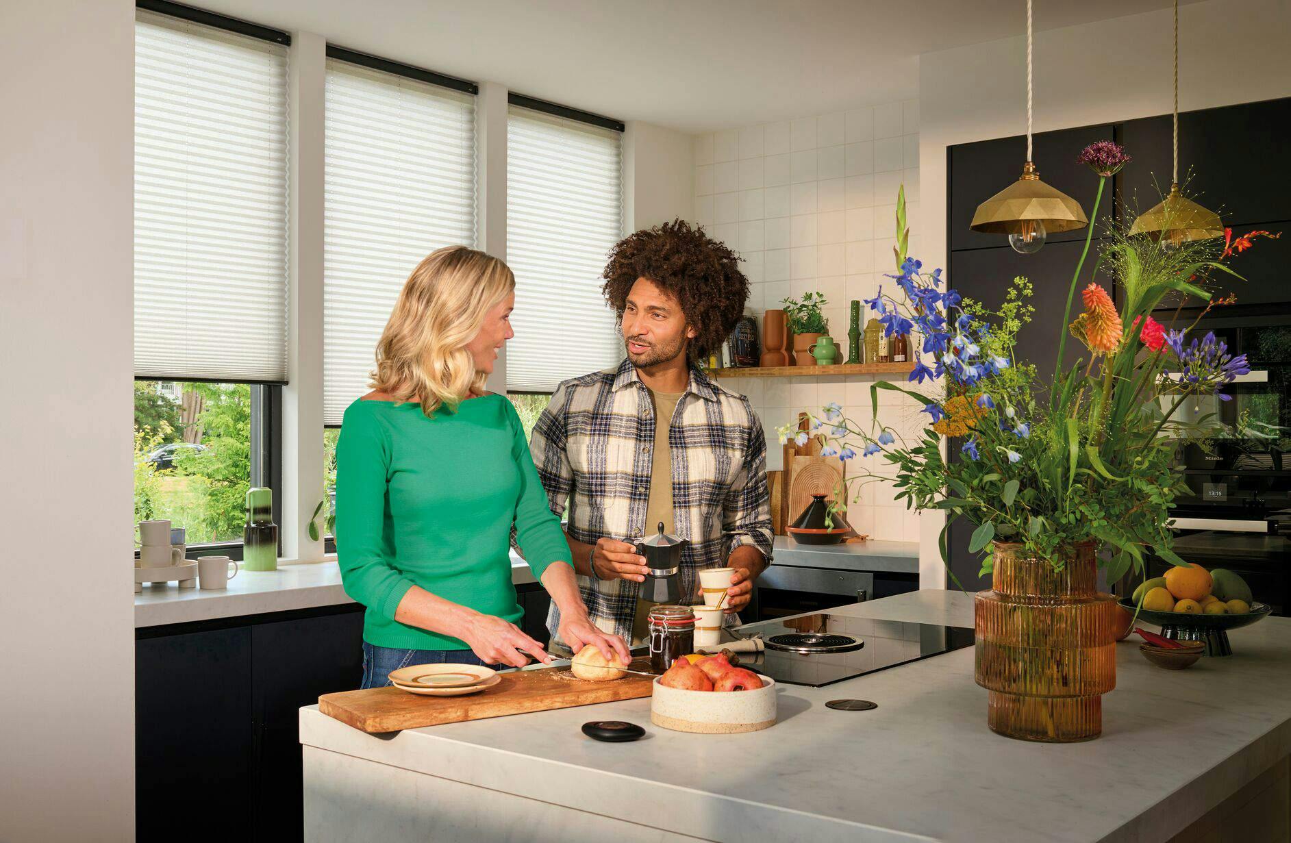 Black powerview pebble remote to operate white plisse shades in a kitchen