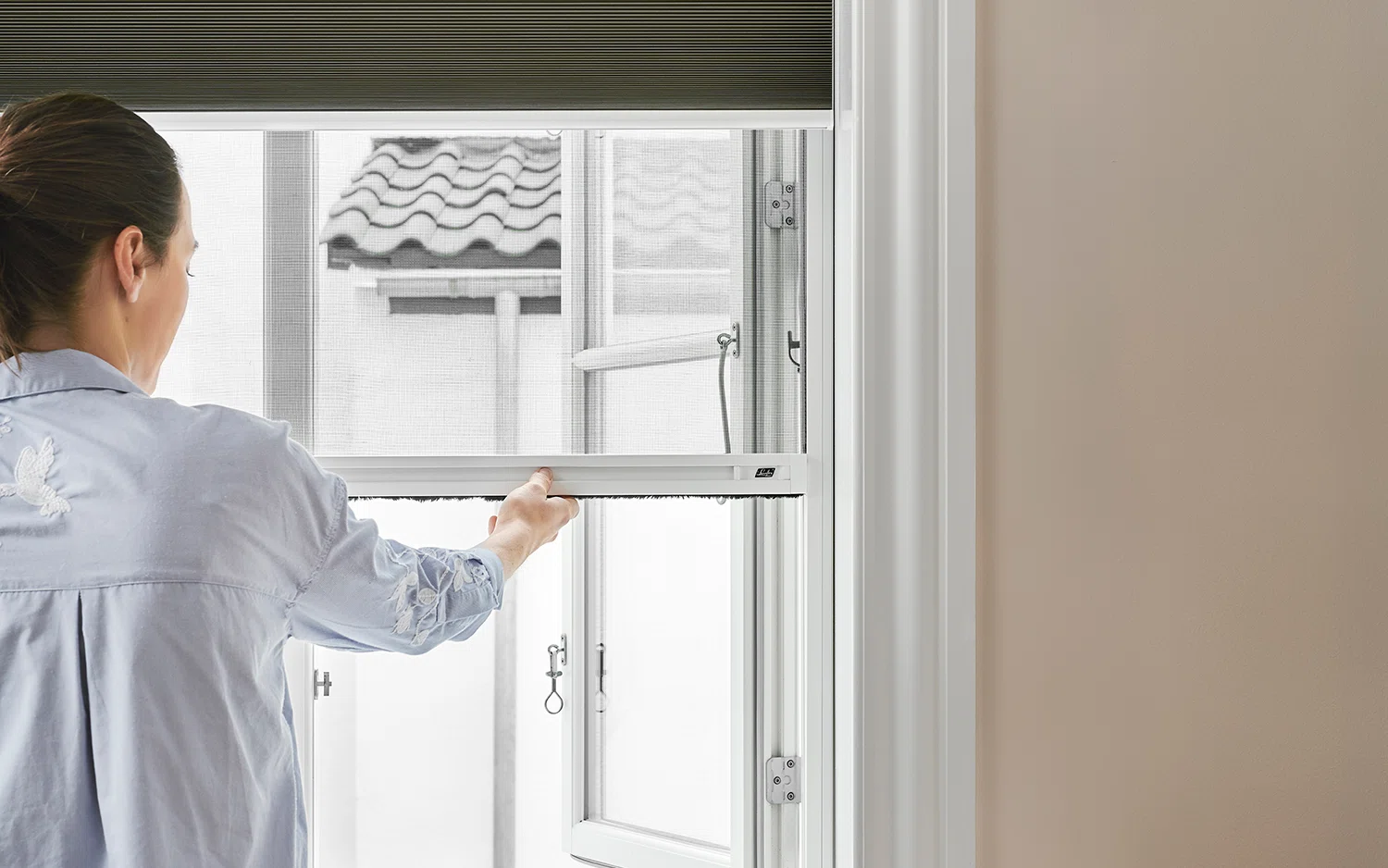 Brown duette shades with insect screen on a window